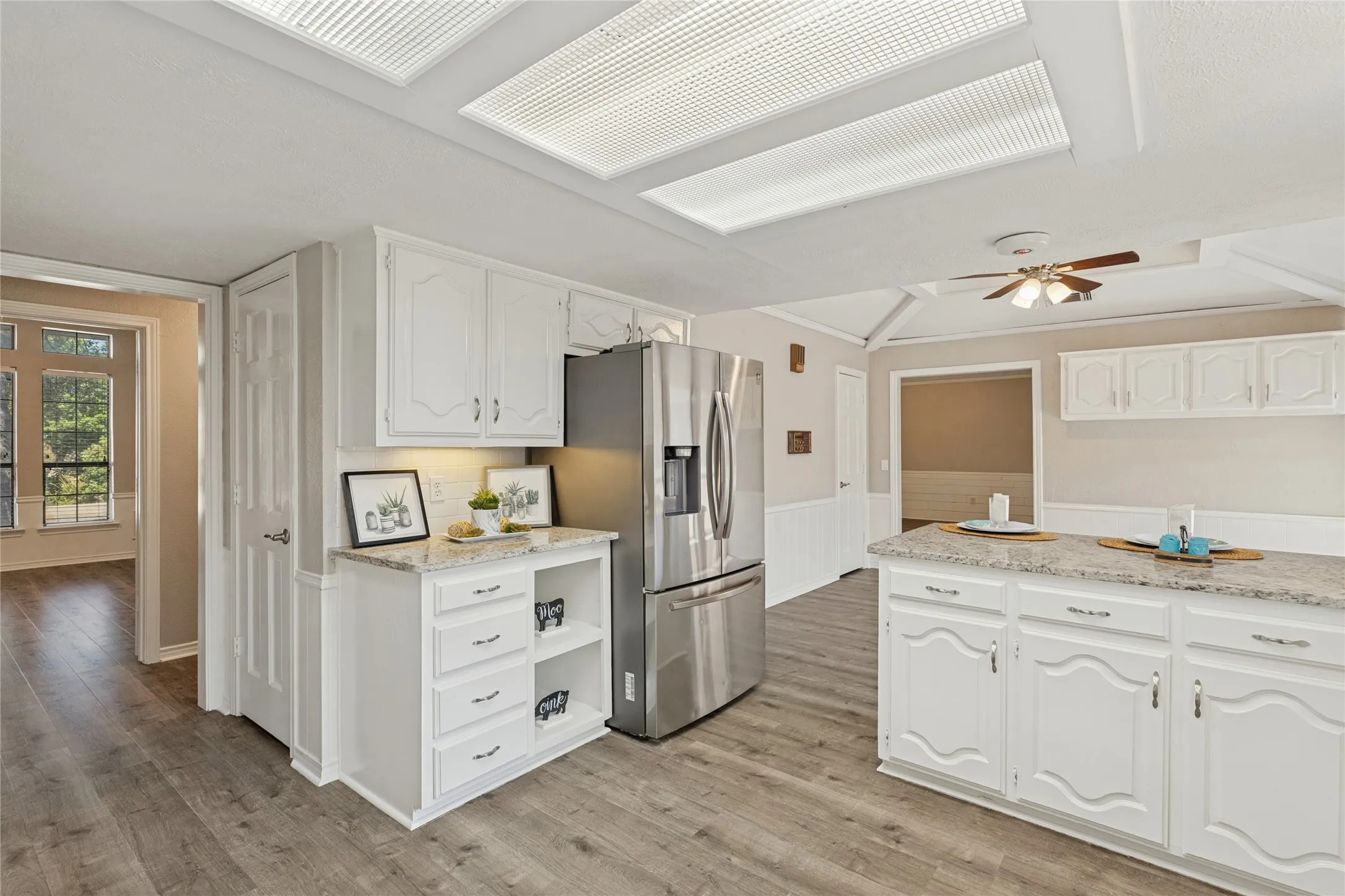 Kitchen featuring white cabinetry, wood-finish flooring, stainless steel refrigerator, and granite countertops, 2 pantries