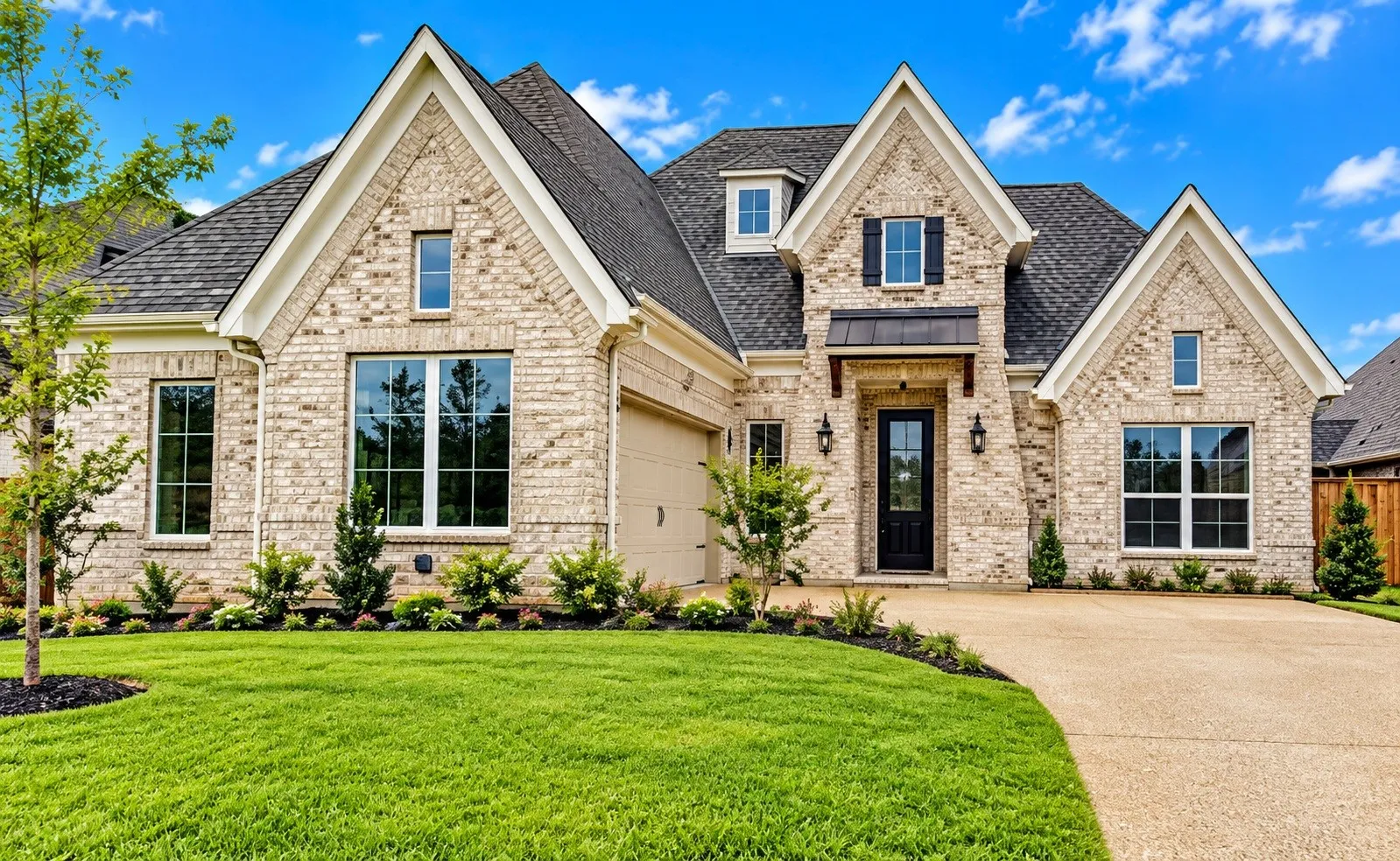 Brick exterior with gabled roof lines, attached garage, well-maintained lawn, and a paved driveway
