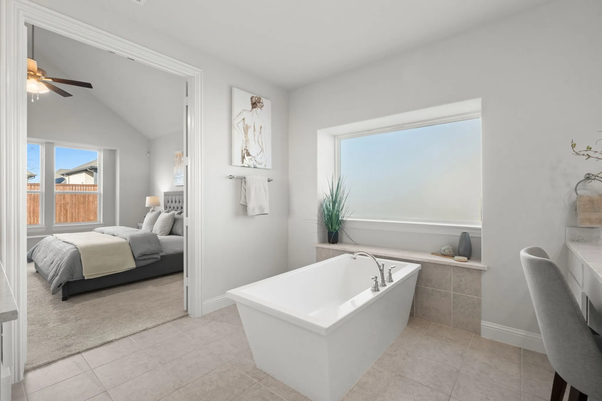 Freestanding bathtub with deck-mounted fixtures, large frosted window, and tile flooring