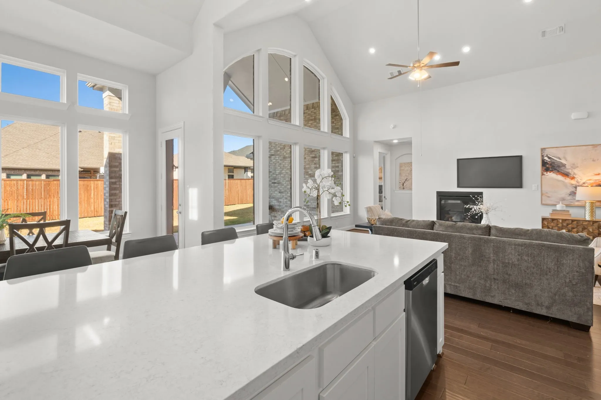 Quartz Kitchen island with a stainless steel sink, white cabinetry, and a light-toned countertop over looking the nook dining and living room