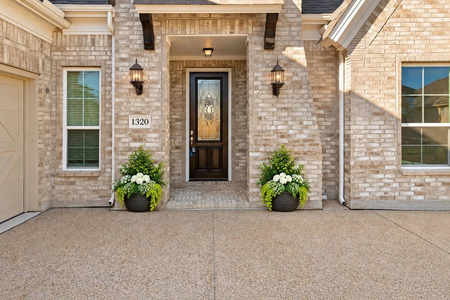 Brick exterior with exposed aggregate driveway and an ornate glass-paneled front door