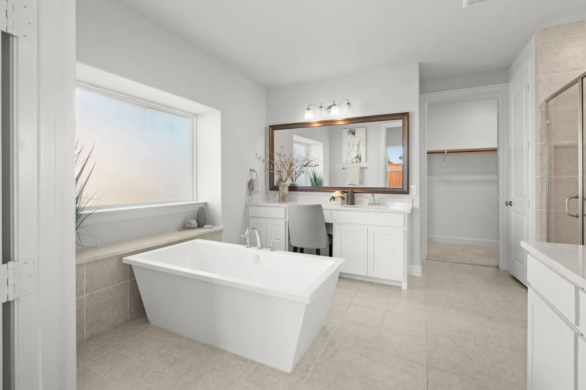 Freestanding soaking tub with tiled surround, dual vanity with undermount sinks, frameless glass shower enclosure, and neutral tile flooring