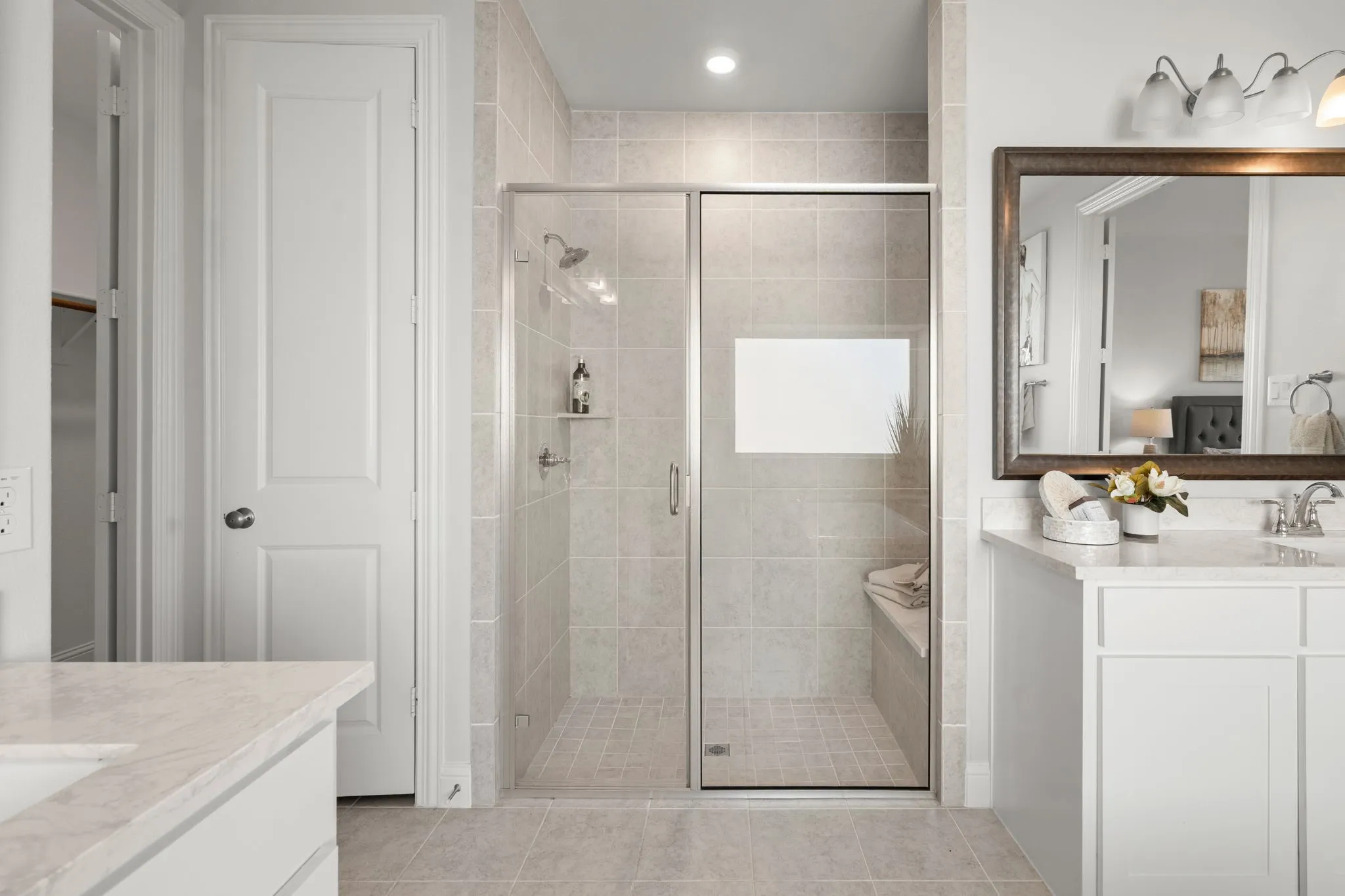 Tiled walk-in shower with glass enclosure, built-in bench, and shelving
