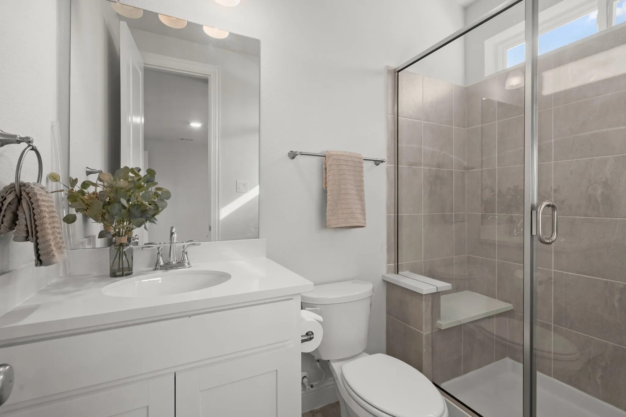 Vanity with an integrated sink, polished chrome faucet, and a large wall-mounted mirror