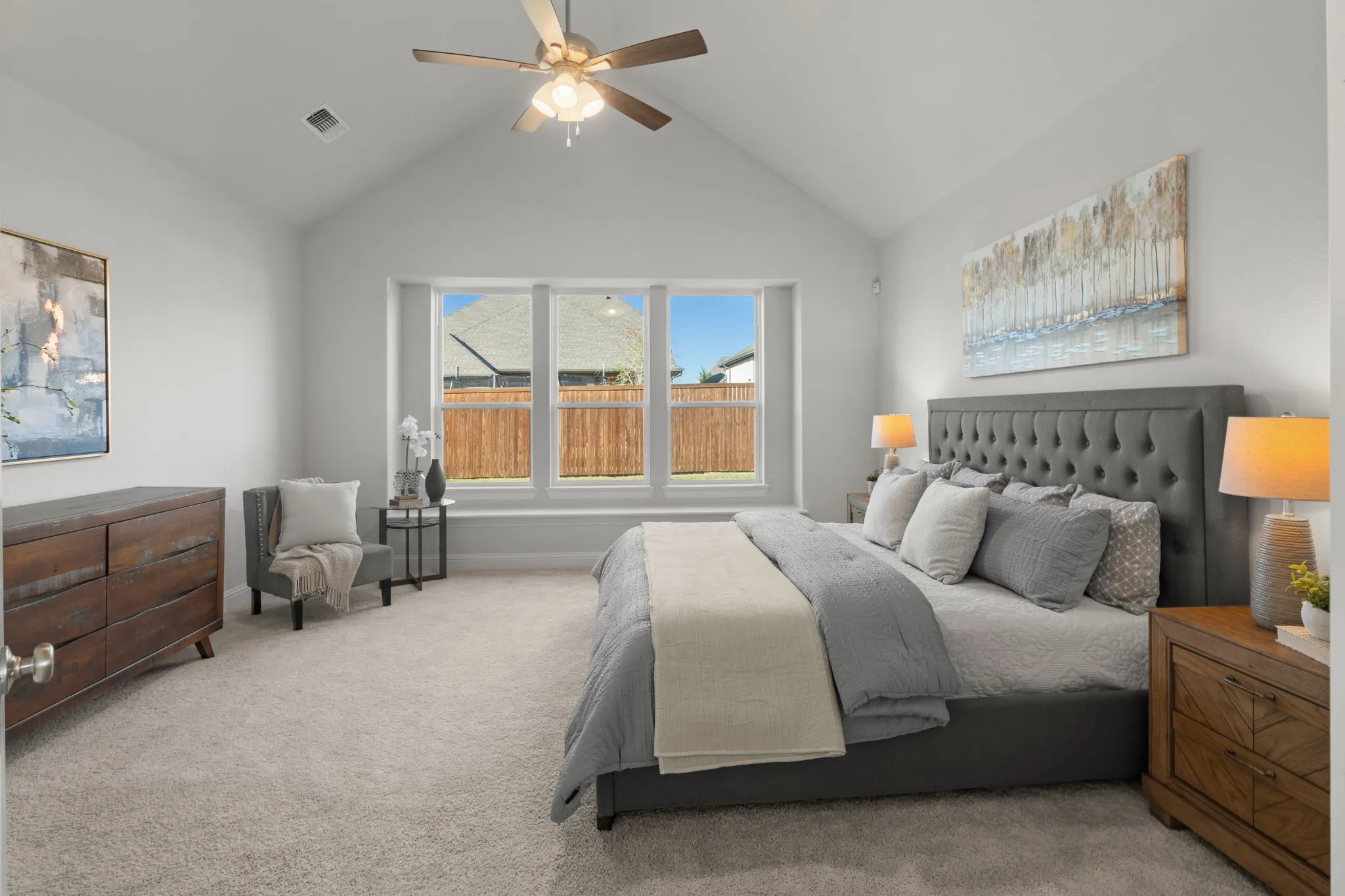 Vaulted ceiling with a ceiling fan, carpeted flooring, and a large bay window