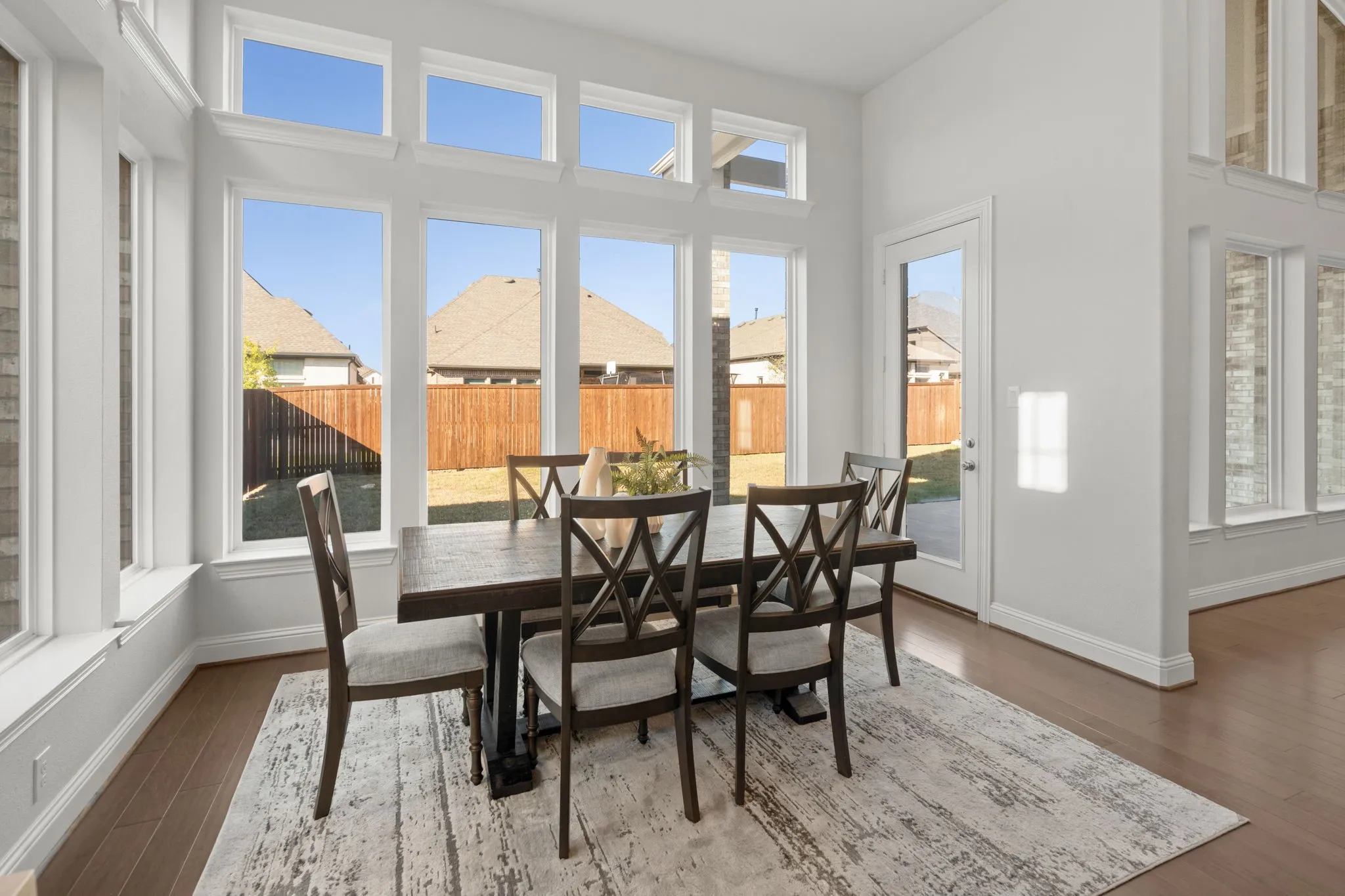 Spacious nook secondary dining room featuring multiple large picture windows, a glass-paneled exterior door, and wood-finish flooring