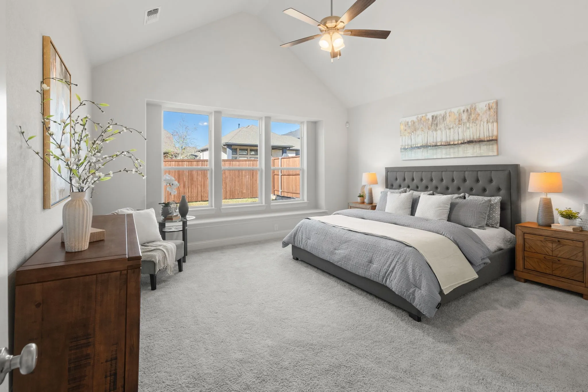 Vaulted ceiling, ceiling fan, carpeted flooring, three large windows, and a window seat