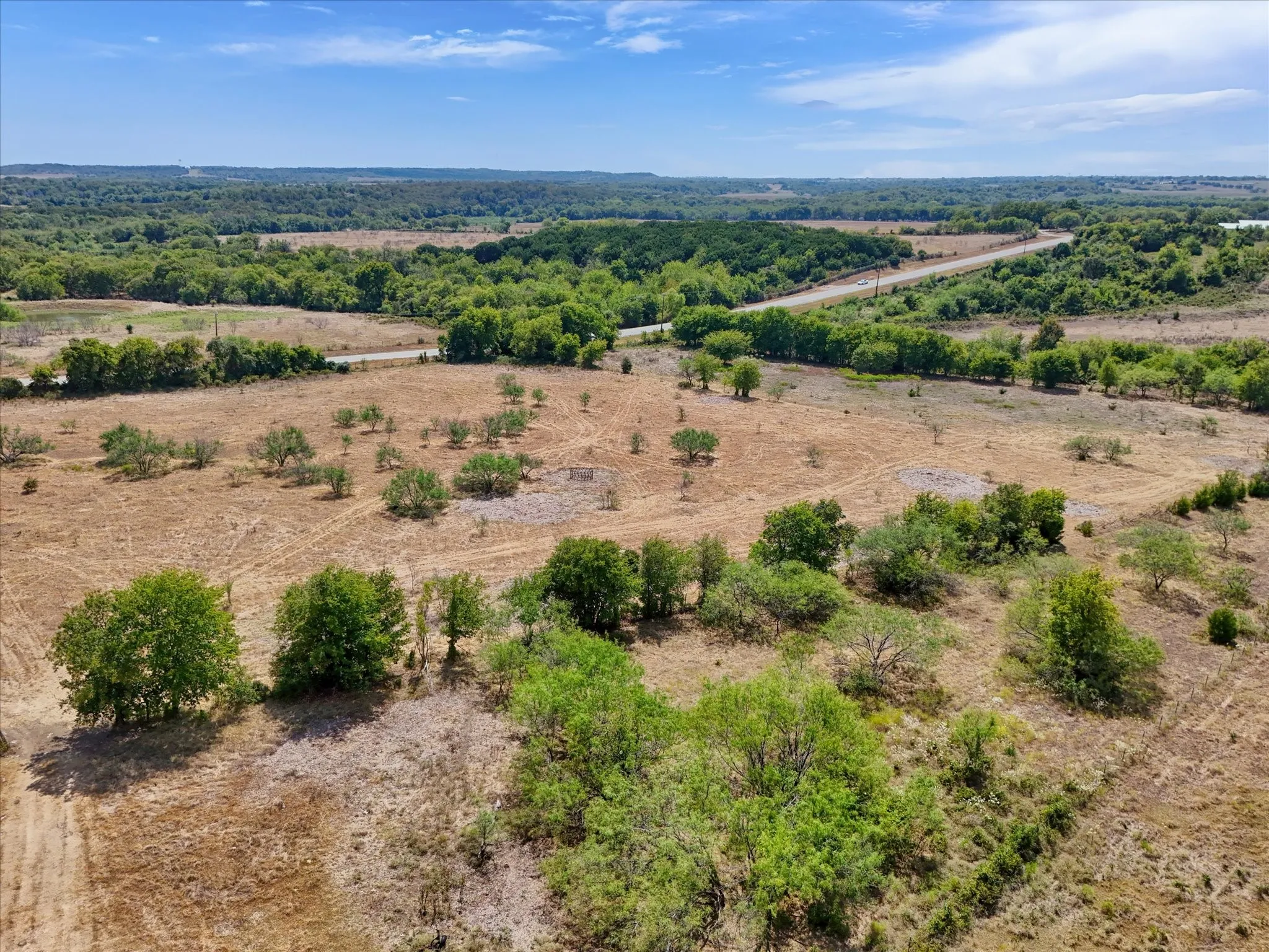 Expansive acreage featuring established trees, varied topography, and a distant road