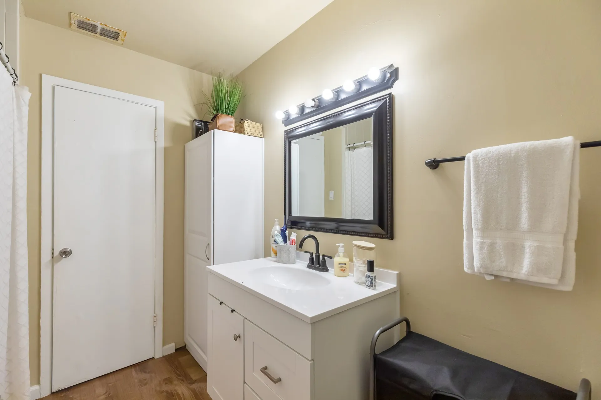 White vanity with integrated sink, dark bronze faucet, and framed mirror