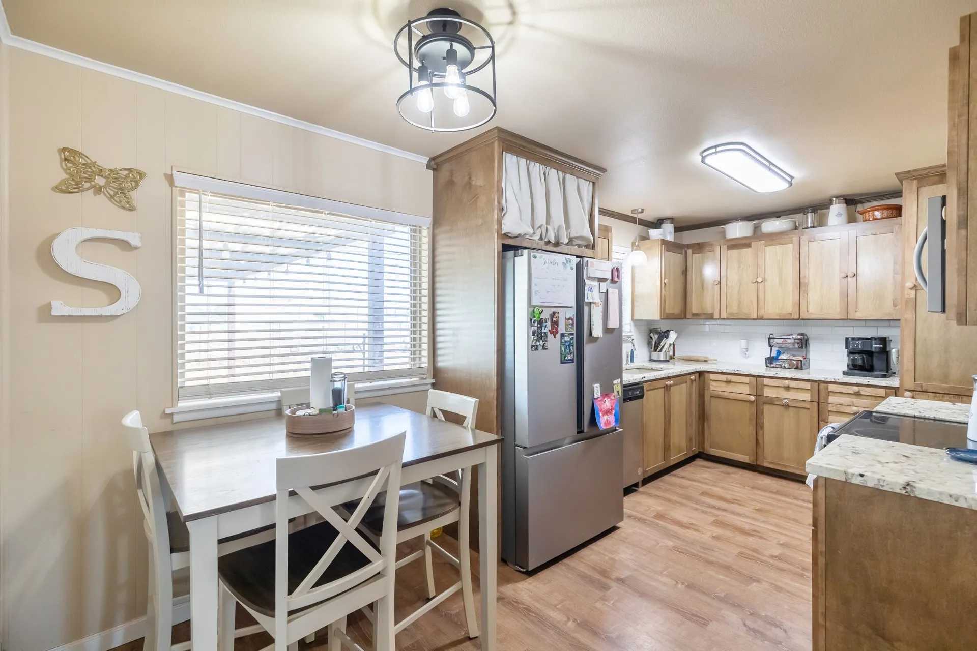 Kitchen featuring wood-finish flooring, light wood cabinetry, white countertops, and a stainless steel refrigerator