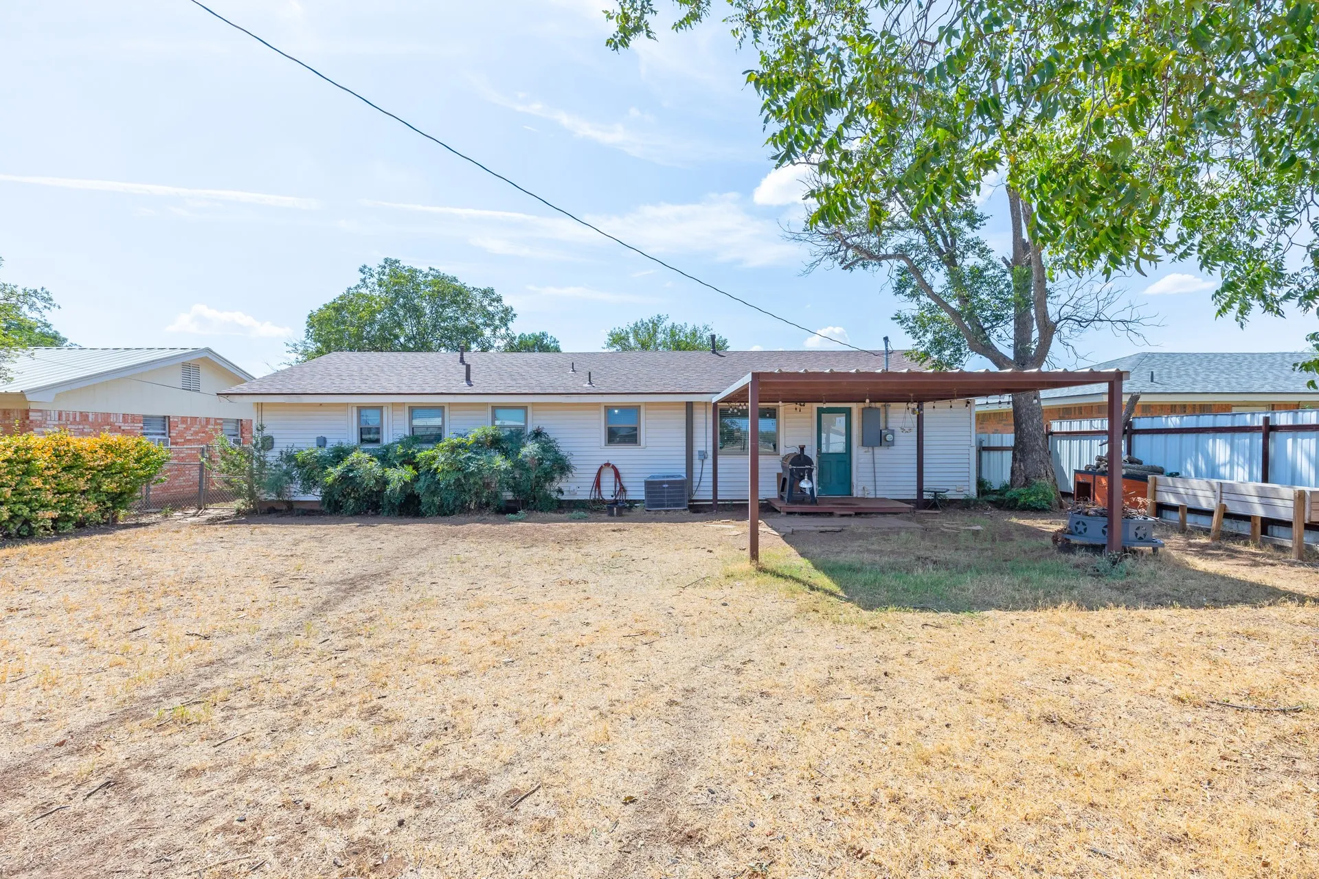 Rear exterior with a covered patio and a large tree