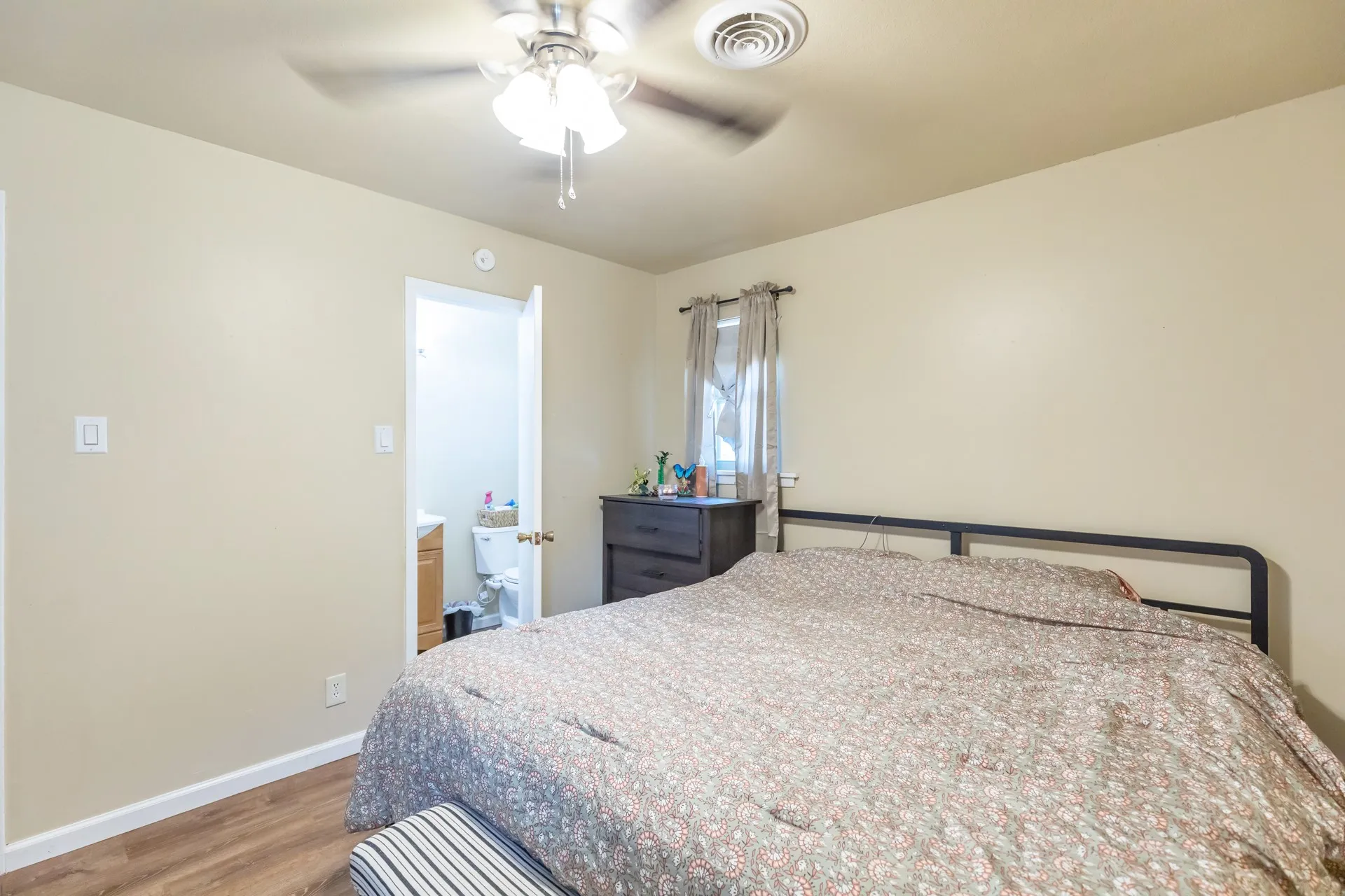 Wood-finish flooring, ceiling fan, and window with curtain rod