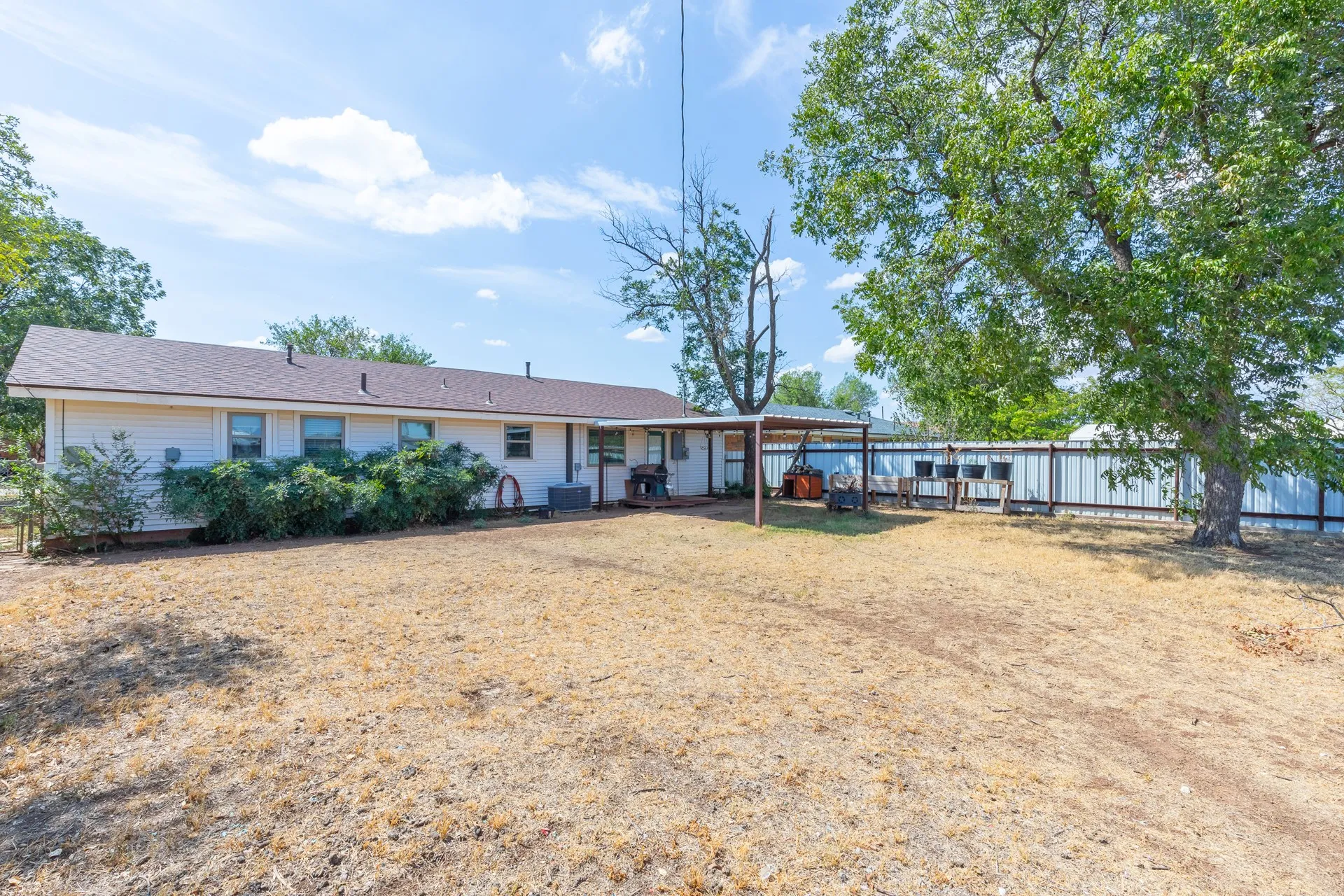 Expansive backyard with a covered patio, a detached covered structure, and mature trees