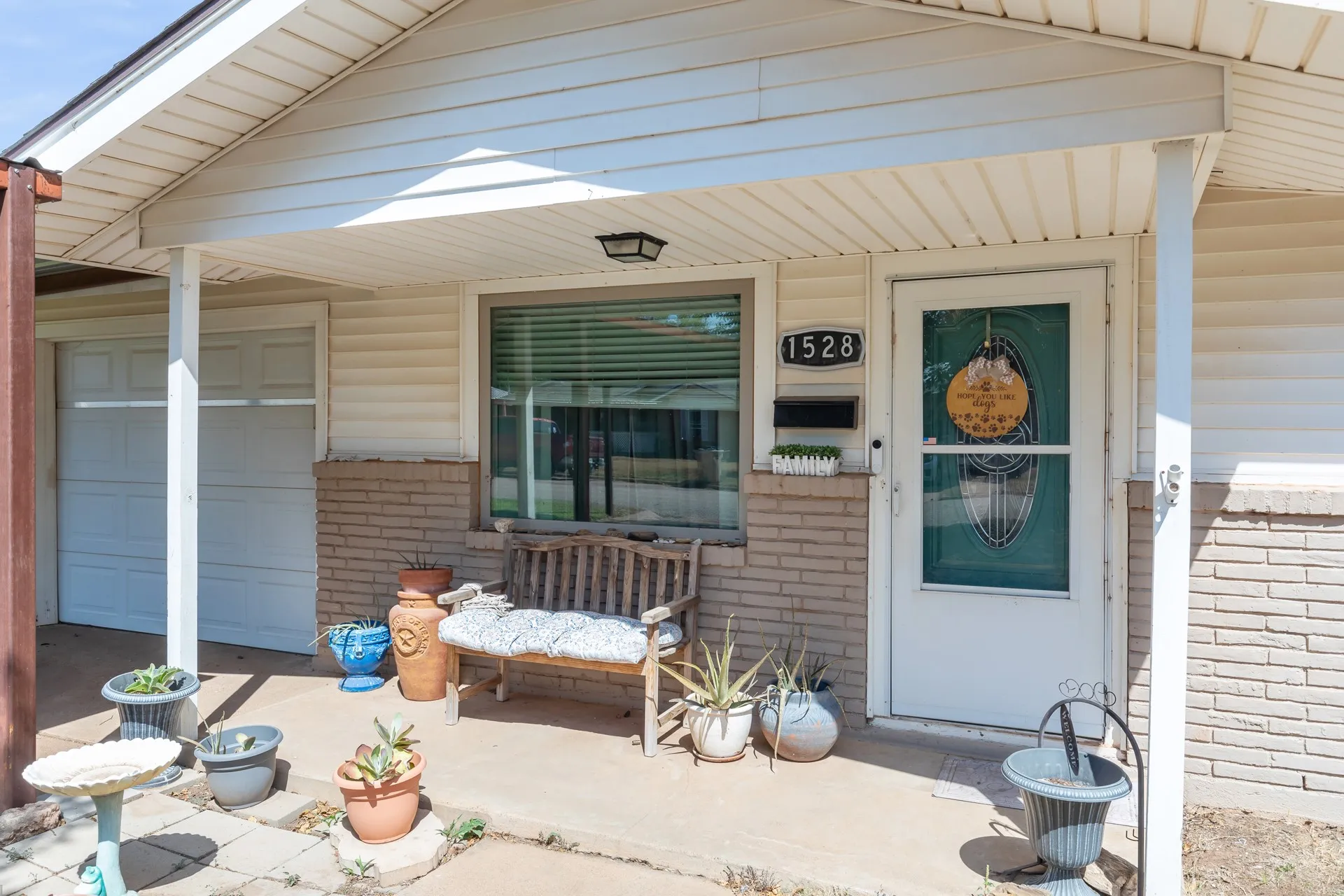 Covered front porch with white siding, brick veneer accent, and a single-car garage