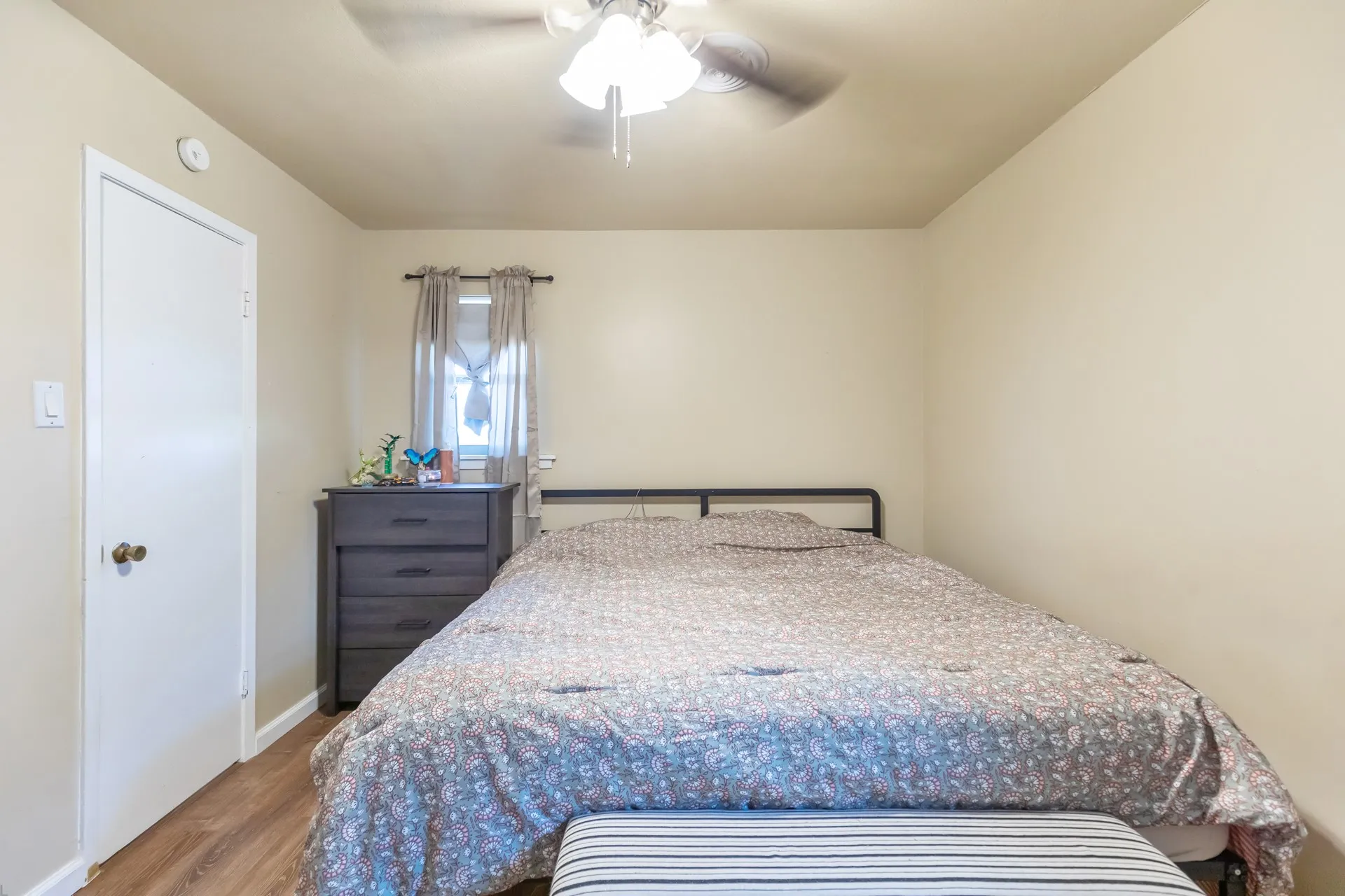 Wood-finish flooring with a ceiling fan light fixture and window