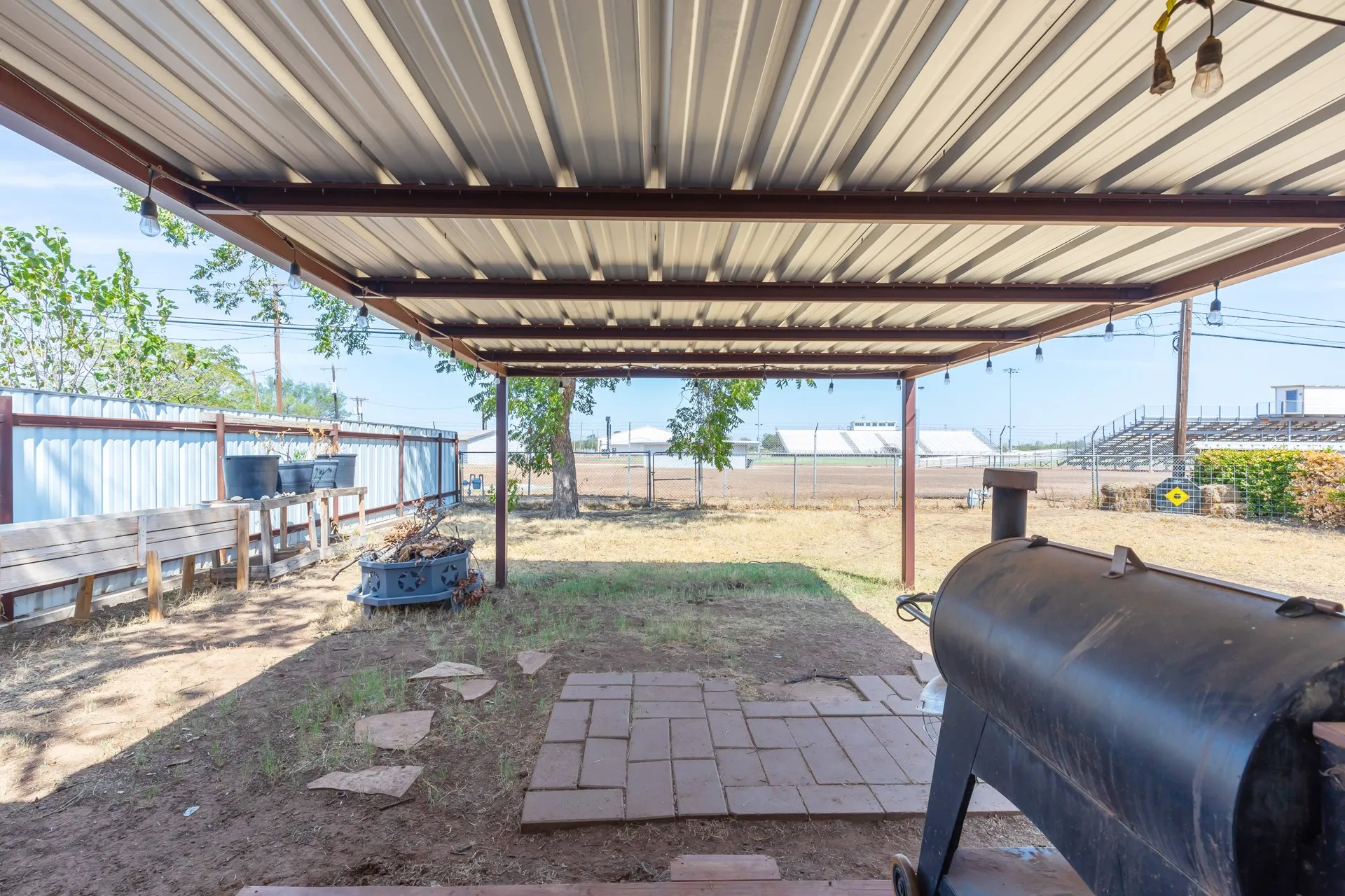 Expansive covered patio featuring a corrugated metal roof, string lighting, and direct access to an open yard space