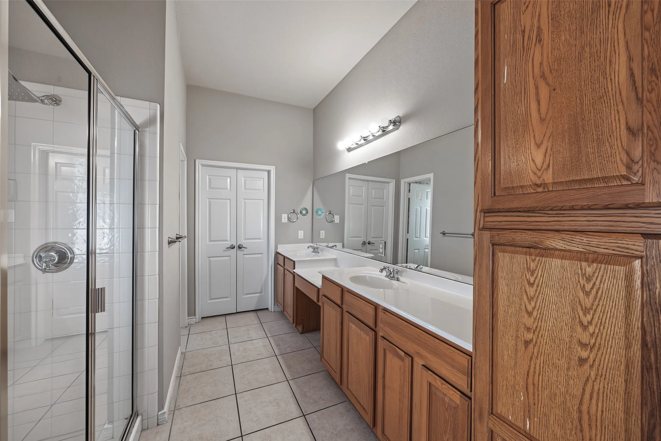 Dual vanity with wood-finish cabinetry, extensive counter space, and integrated sinks