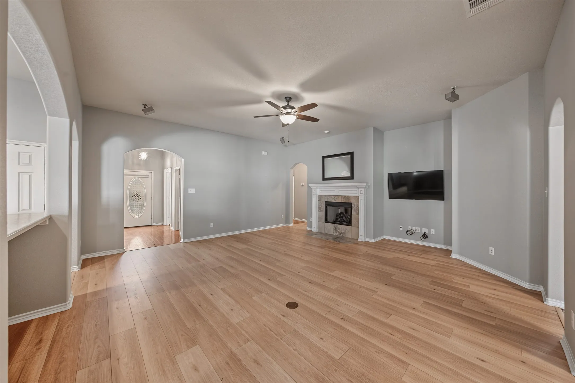 Spacious living area featuring wood-finish flooring, a ceiling fan, and recessed lighting