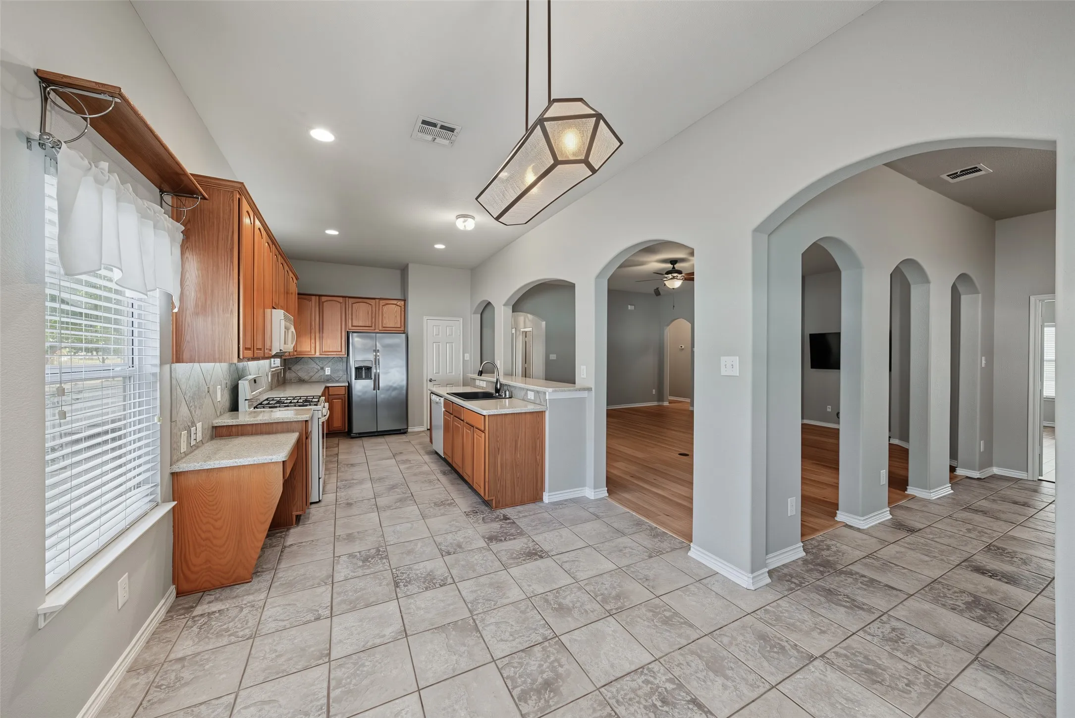 Kitchen featuring wood-finish cabinetry, stainless steel appliances, tile flooring, and a stone countertop