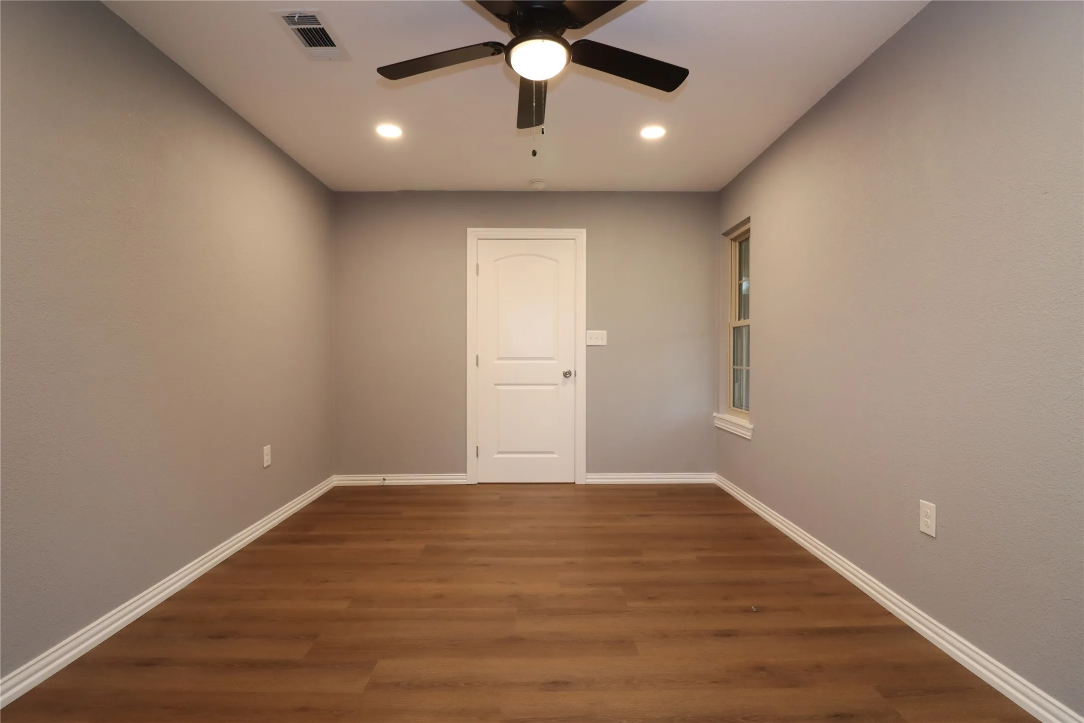 Wood-finish flooring with white baseboards, recessed lighting, and a ceiling fan