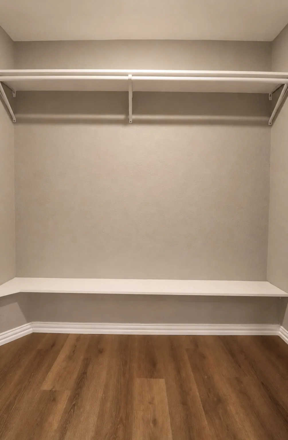 Wood-finish flooring, built-in shelving, two hanging rods, and neutral wall tones