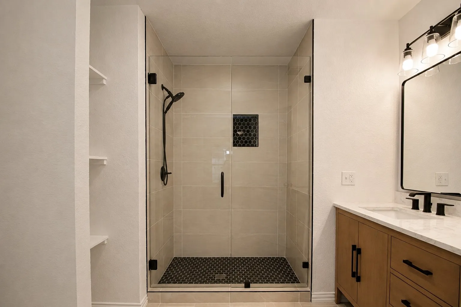 Glass-enclosed shower with matte black fixtures and a mosaic tile floor