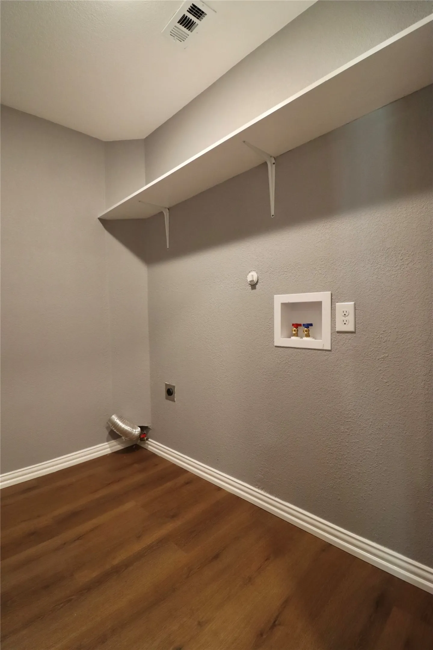 Wood-finish flooring with white trim, a long white shelf, and light gray walls