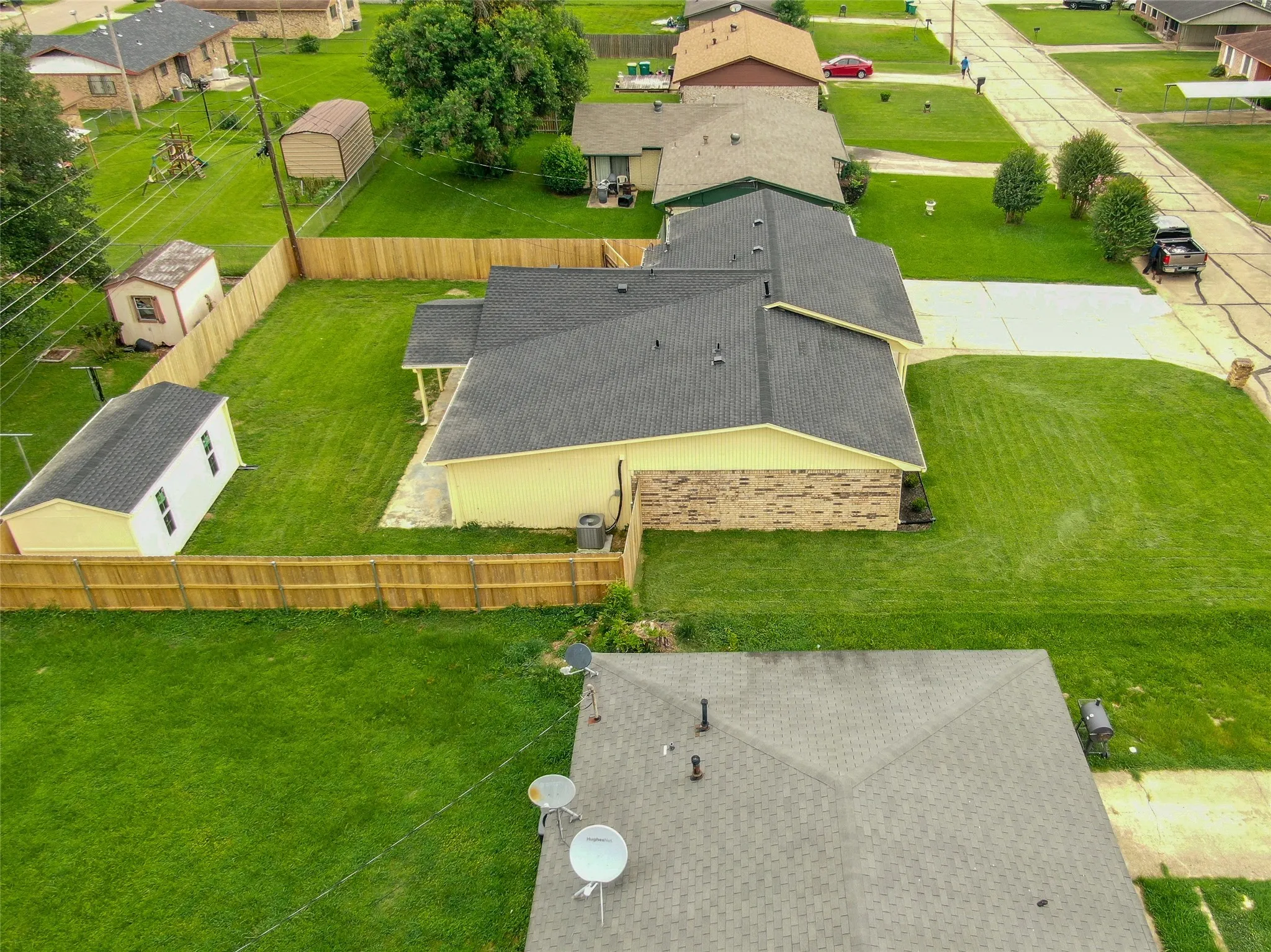 Expansive rear yard featuring a wood fence, a detached storage building, and a manicured lawn