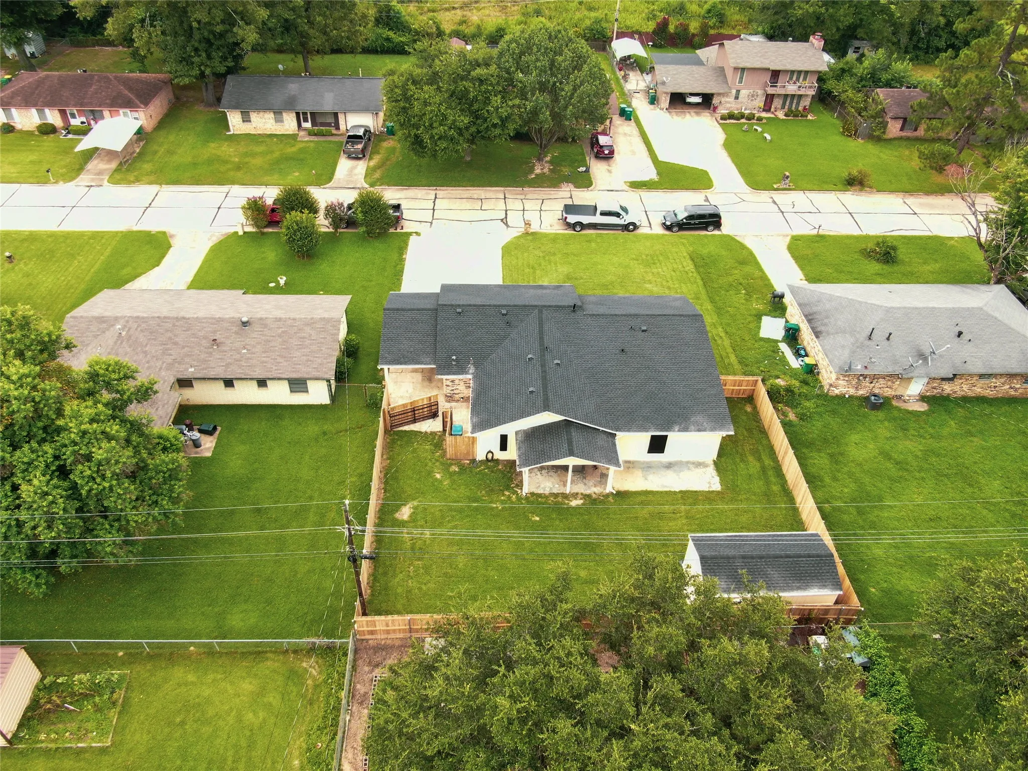 Newly constructed residence featuring a dark shingle roof, light-colored exterior, and an expansive grassy yard