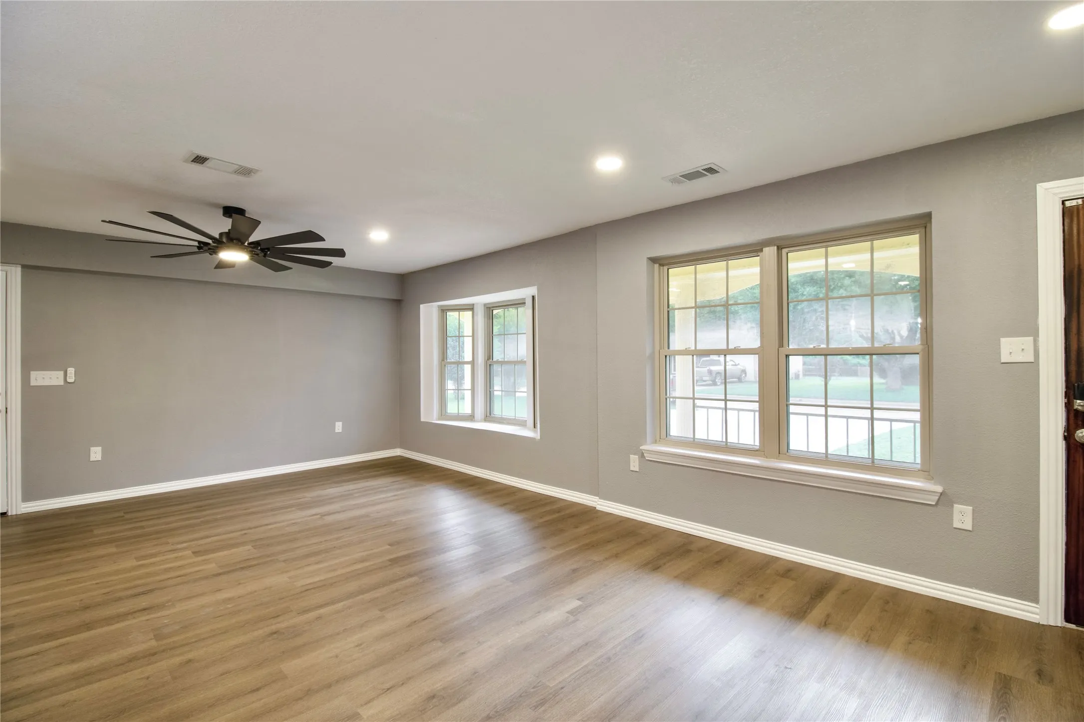 Wood-finish flooring, recessed lighting, ceiling fan, and multiple windows