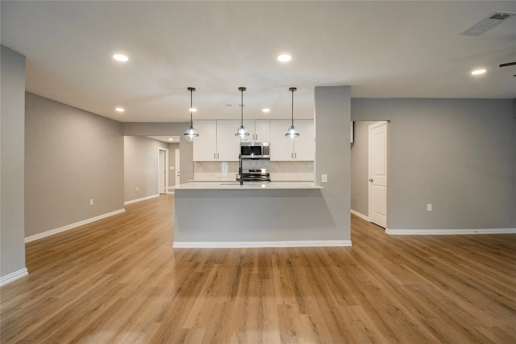 Open-concept layout featuring wood-finish flooring, recessed lighting, and a kitchen island with pendant lighting