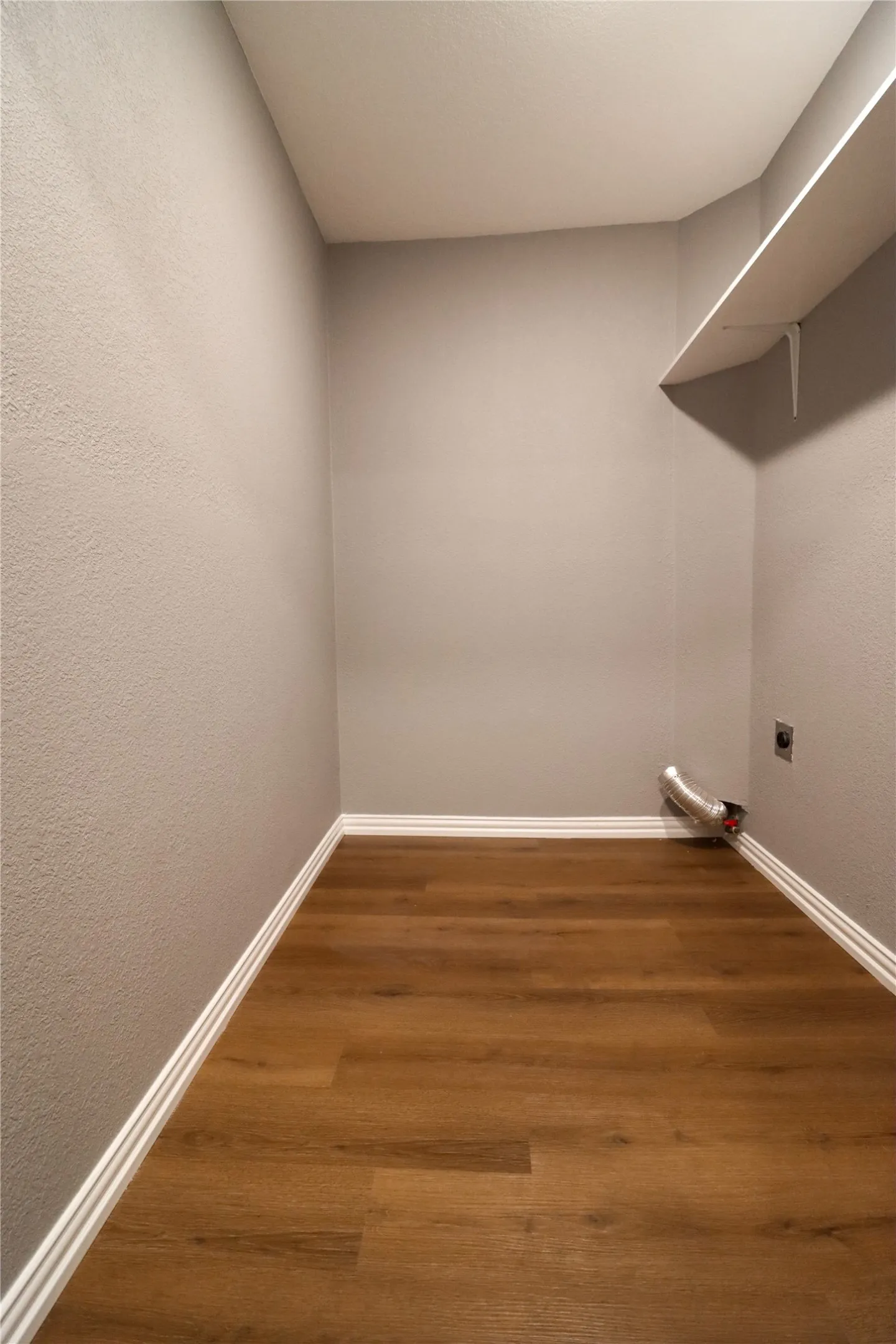 Wood-finish flooring, light gray wall finish, white baseboards, and built-in shelving