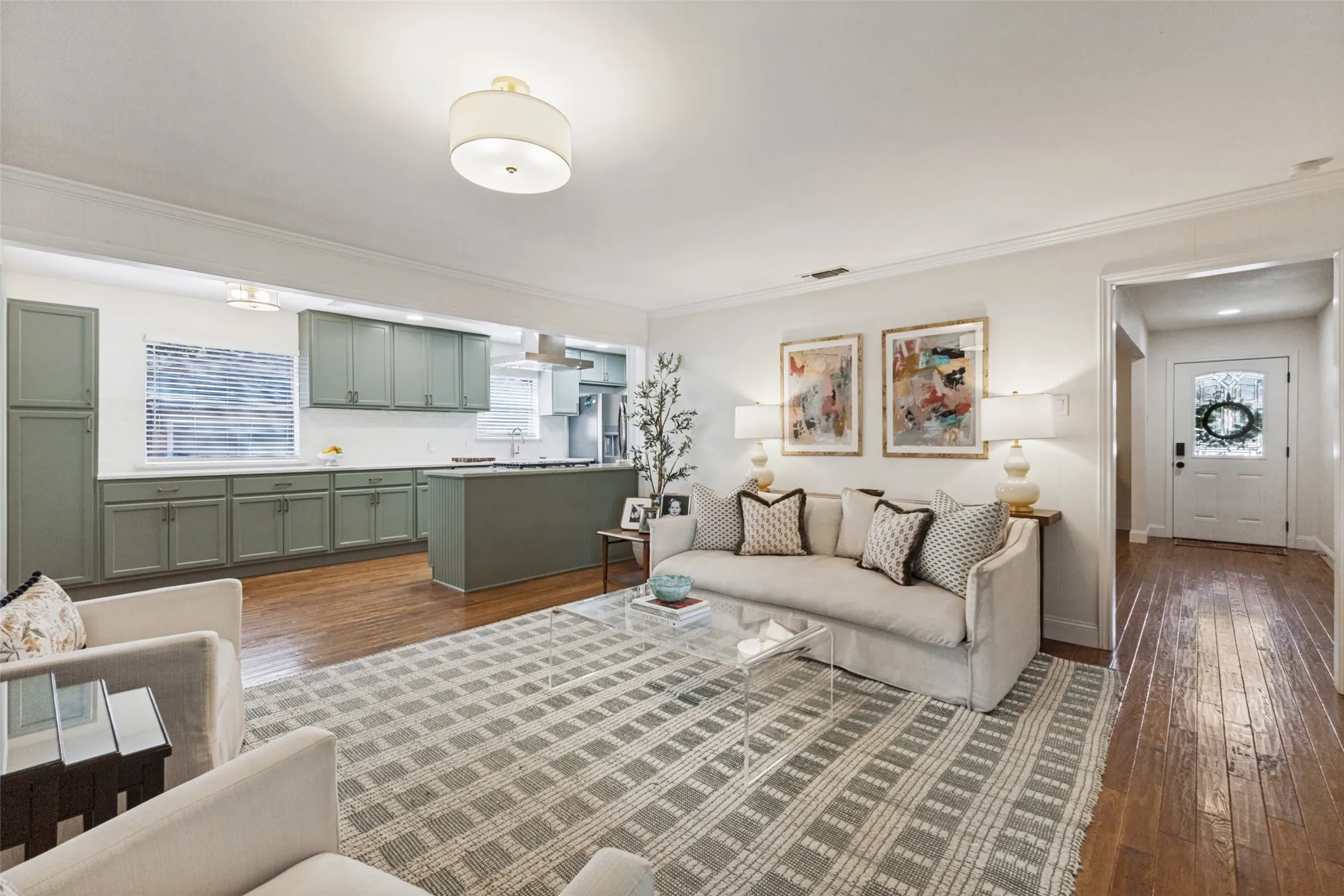 Open-concept layout featuring hardwood flooring, recessed lighting, and a kitchen with olive cabinetry and a center island