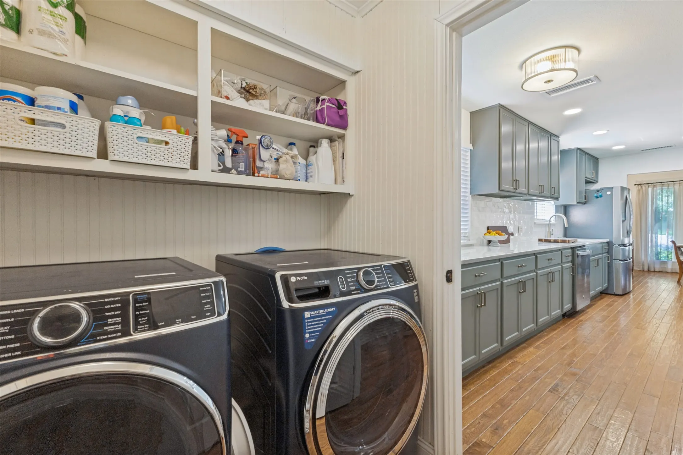 Built-in shelving, paneled walls, wood-finish flooring, recessed lighting, and gray cabinetry with hardware