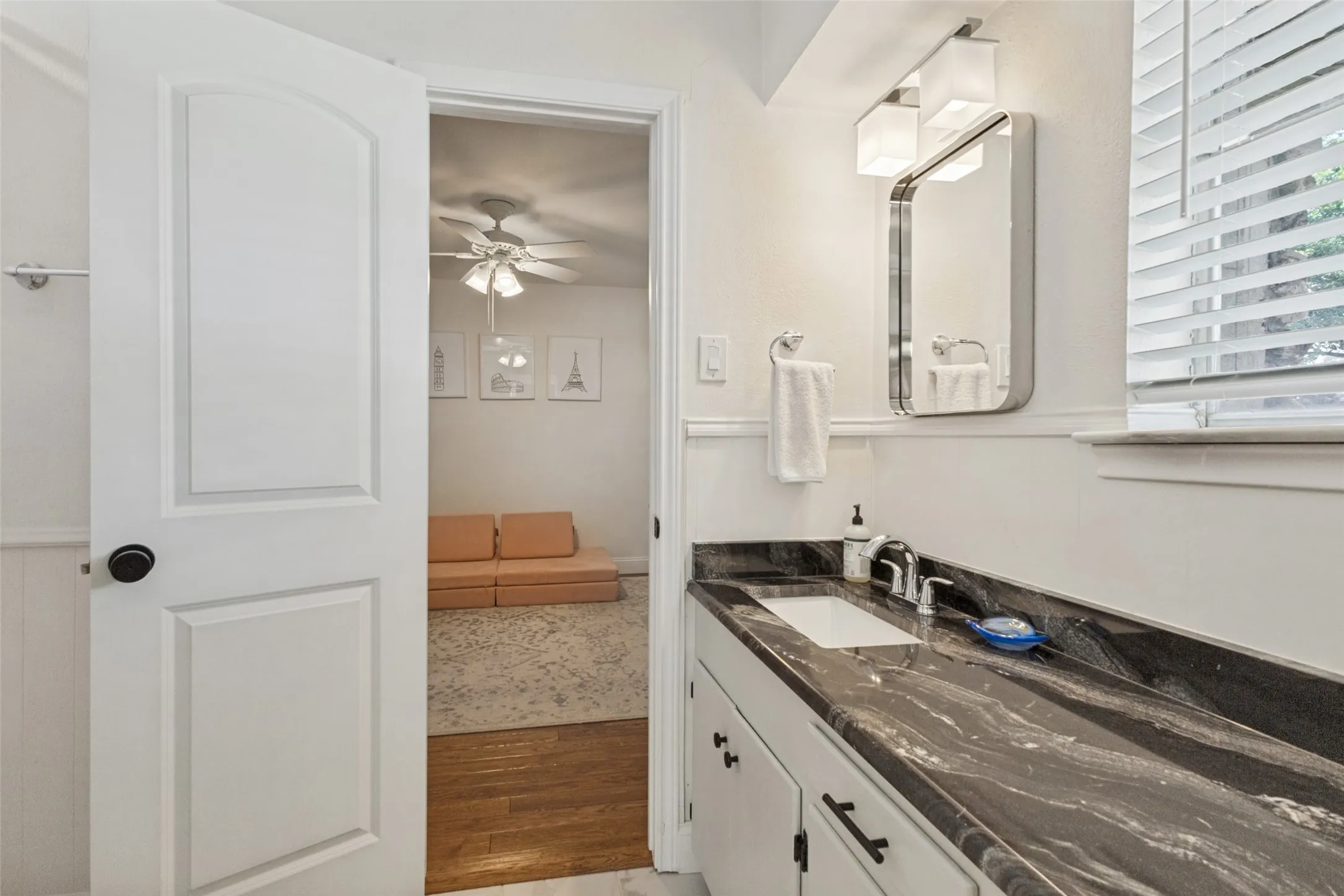Vanity with dark, patterned countertop, undermount sink, and chrome faucet