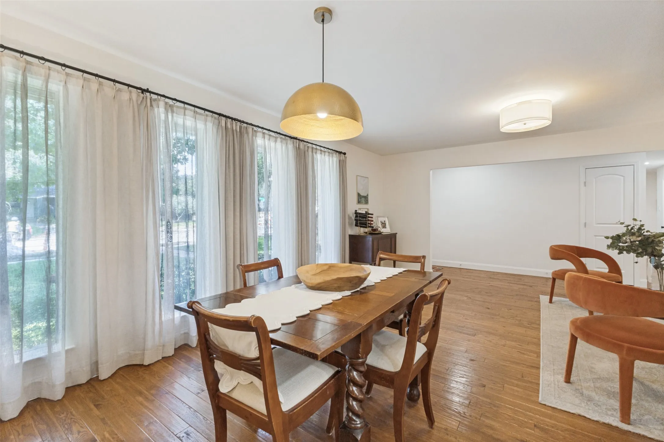 Hardwood flooring, expansive windows with custom drapery, a central pendant light fixture, recessed lighting, and a white interior door