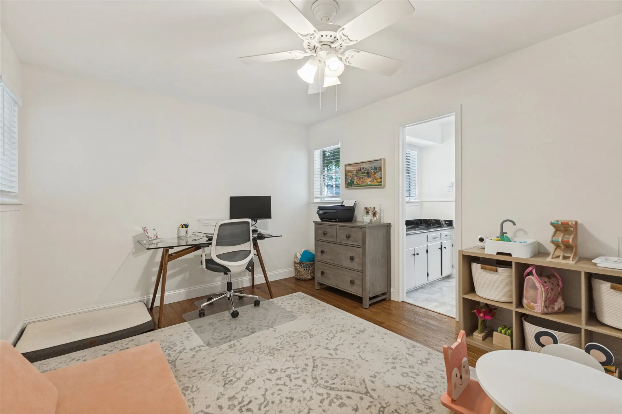 Hardwood-finish flooring, ceiling fan with integrated lighting, and multiple windows with blinds