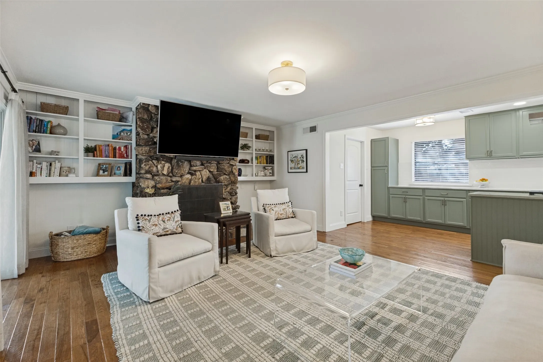 Stone-clad fireplace with hearth, built-in shelving, wood-finish flooring, and recessed lighting