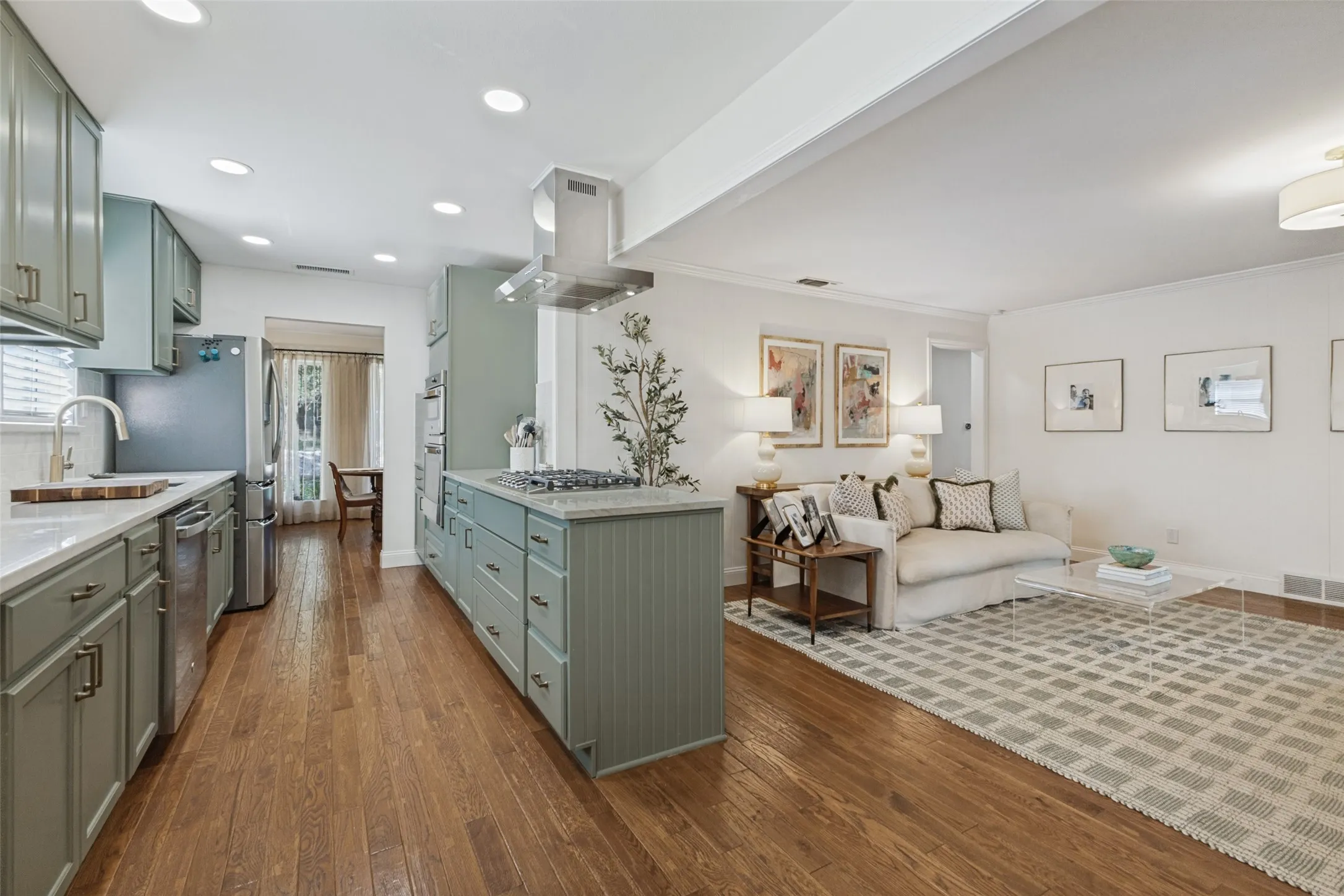 Galley kitchen with light green cabinetry, stainless steel appliances, and a gas cooktop
