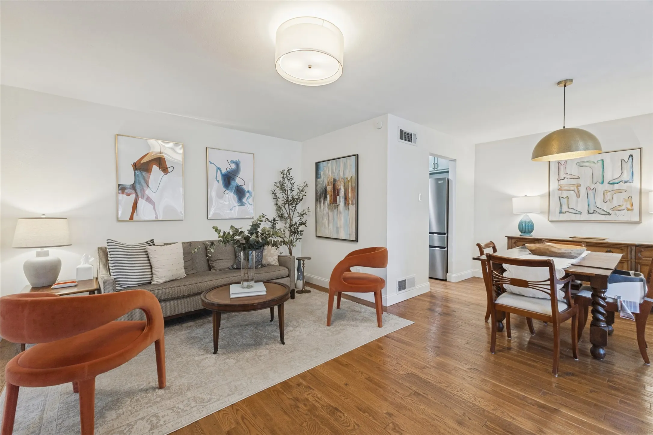 Hardwood flooring throughout, recessed lighting in the living area, and a dining area with a brass pendant light fixture
