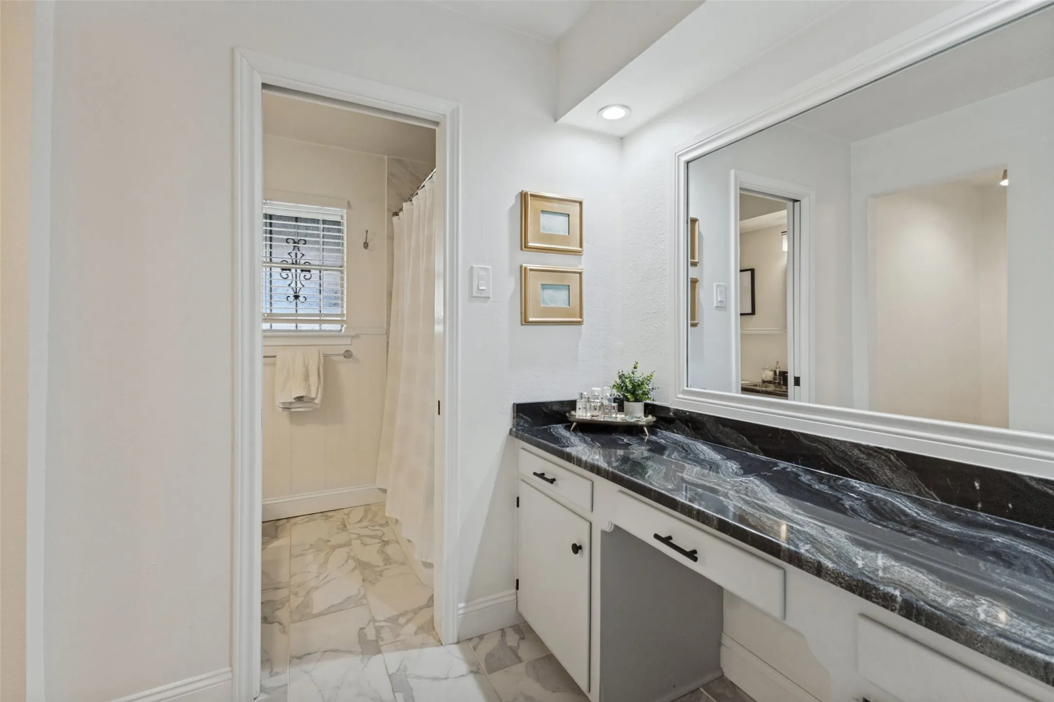 White cabinetry with dark hardware and a black patterned countertop