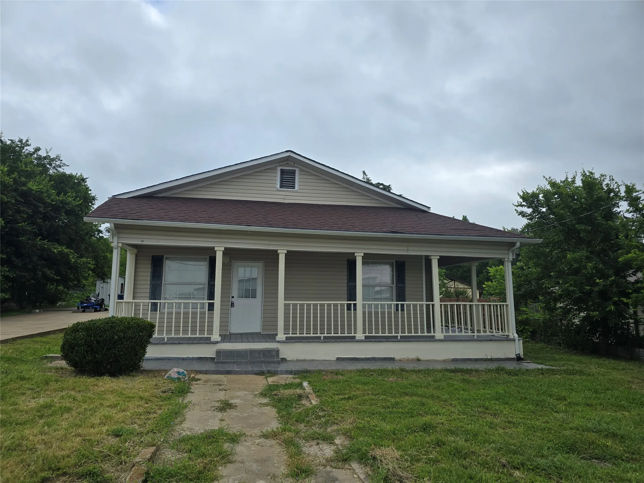 View of front of house featuring covered porch, a front yard, and roof with shingles