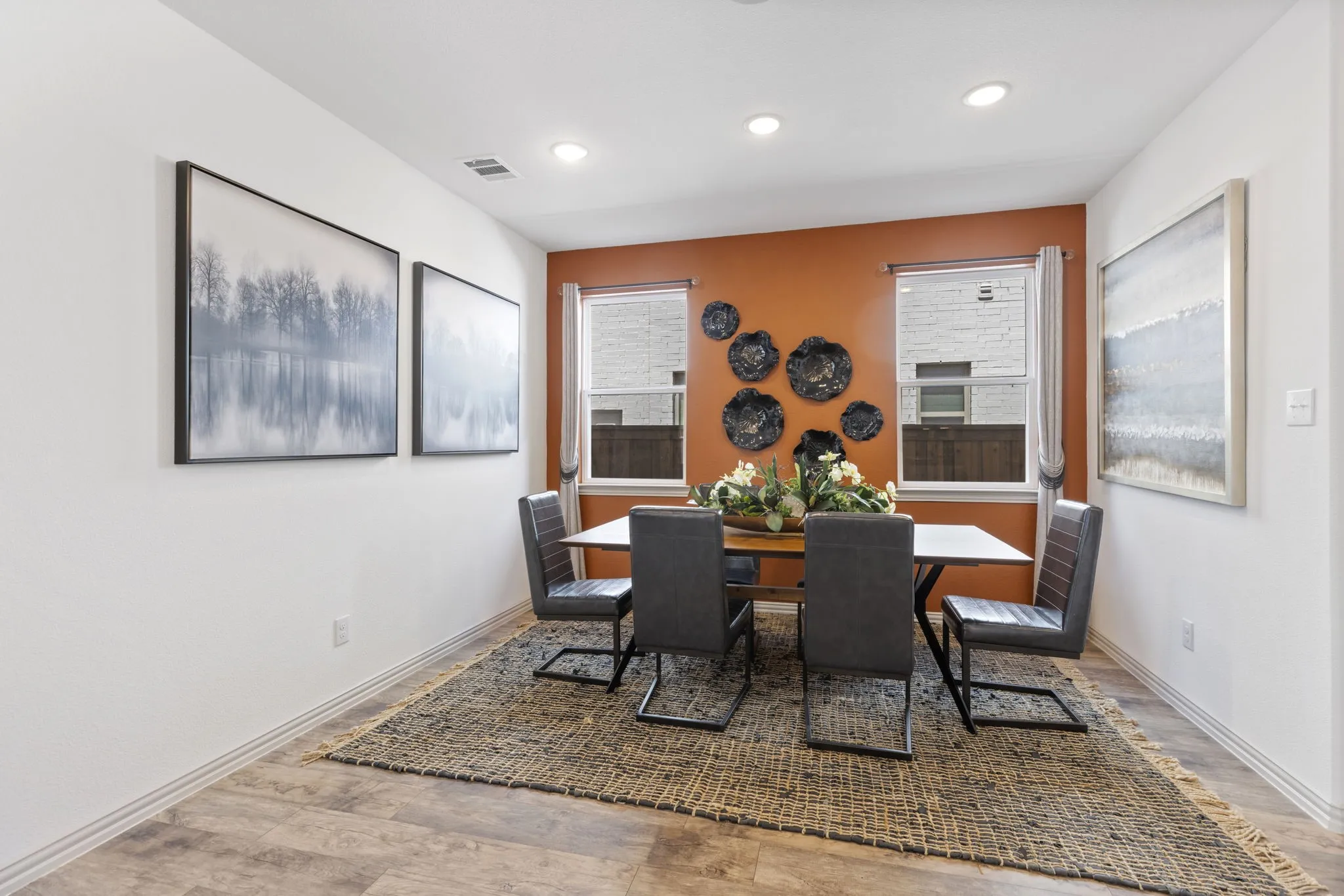 Recessed lighting, warm accent wall, dual windows, wood-finish flooring, and white baseboards