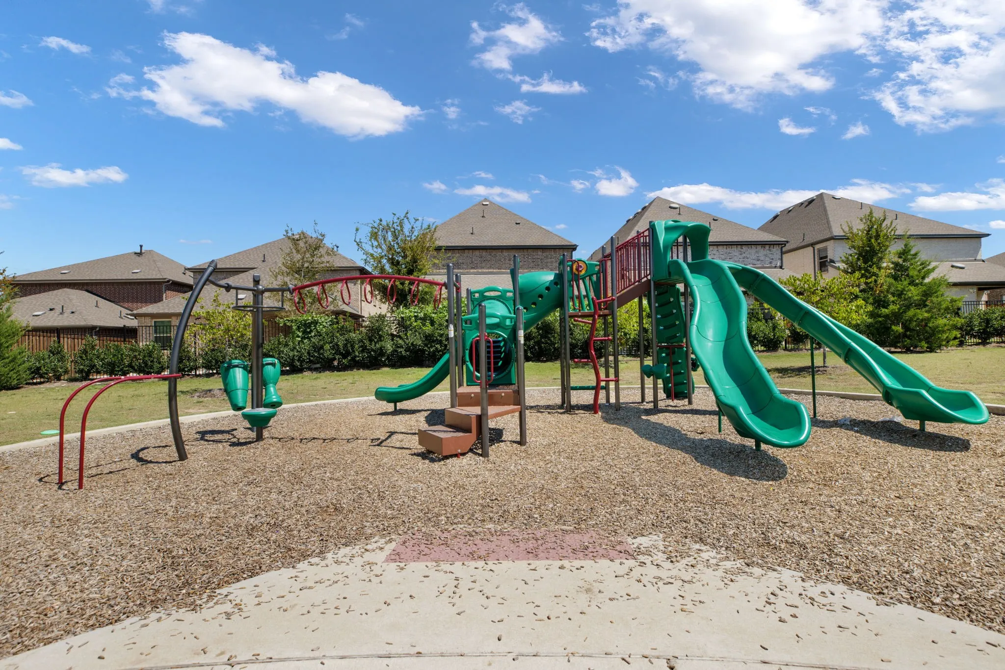Community playground featuring multiple slides, climbing structures, and a wood chip surface