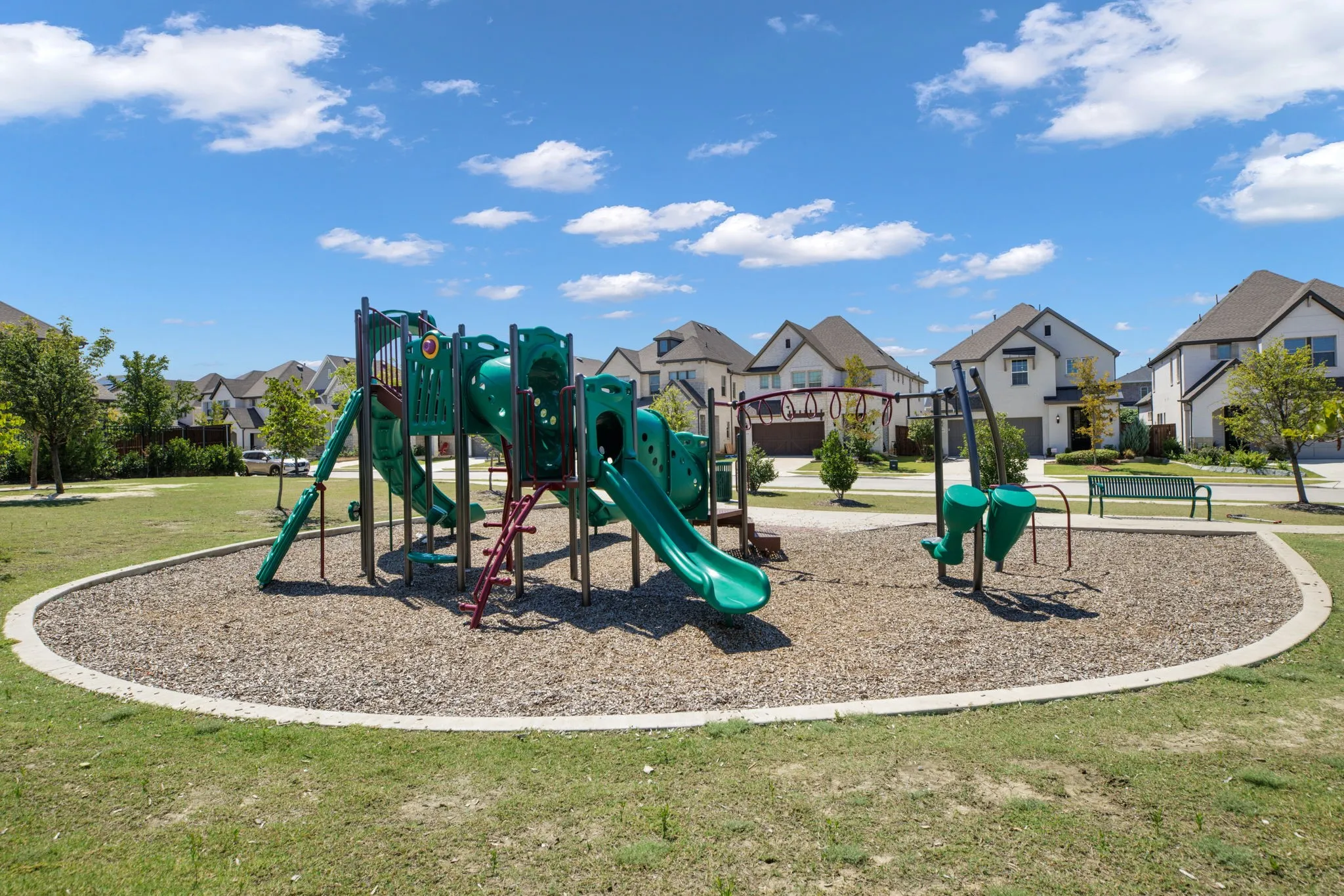 Community playground featuring a multi-level play structure, slides, and swing sets