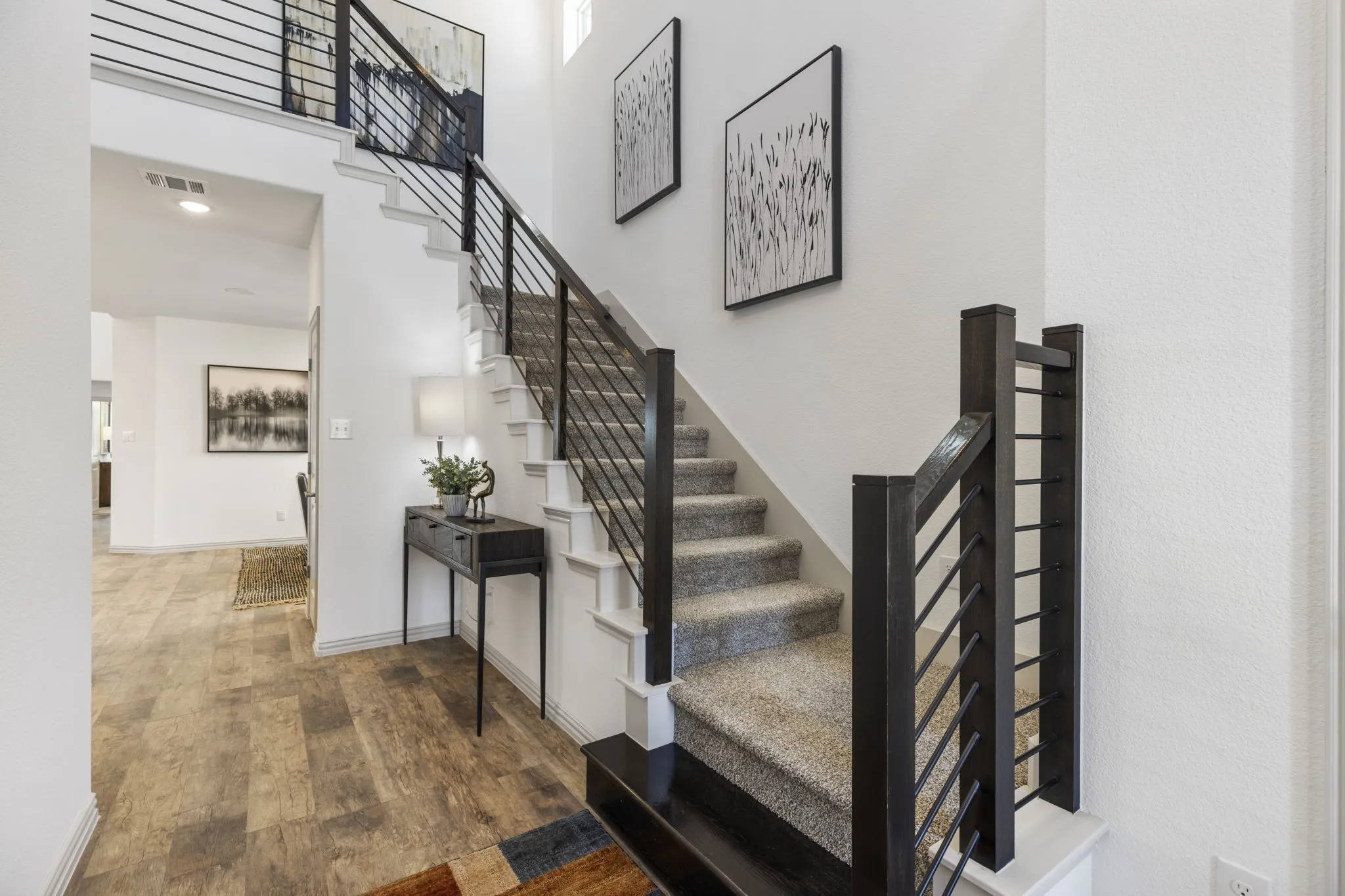 Staircase with horizontal metal balusters, carpeted treads, and wood-finish newel posts