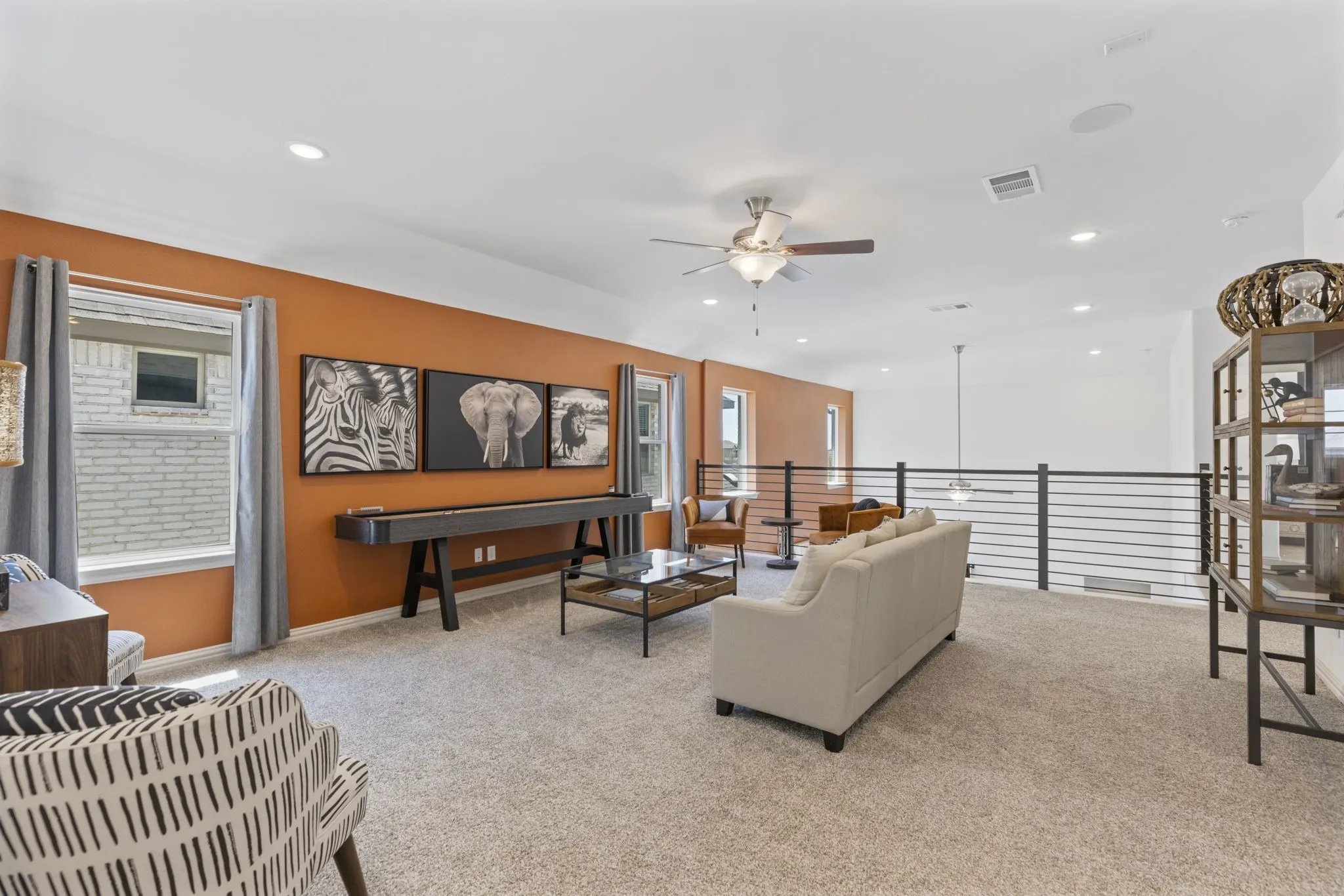 Spacious loft area with carpeting, recessed lighting, ceiling fan, and horizontal metal railings
