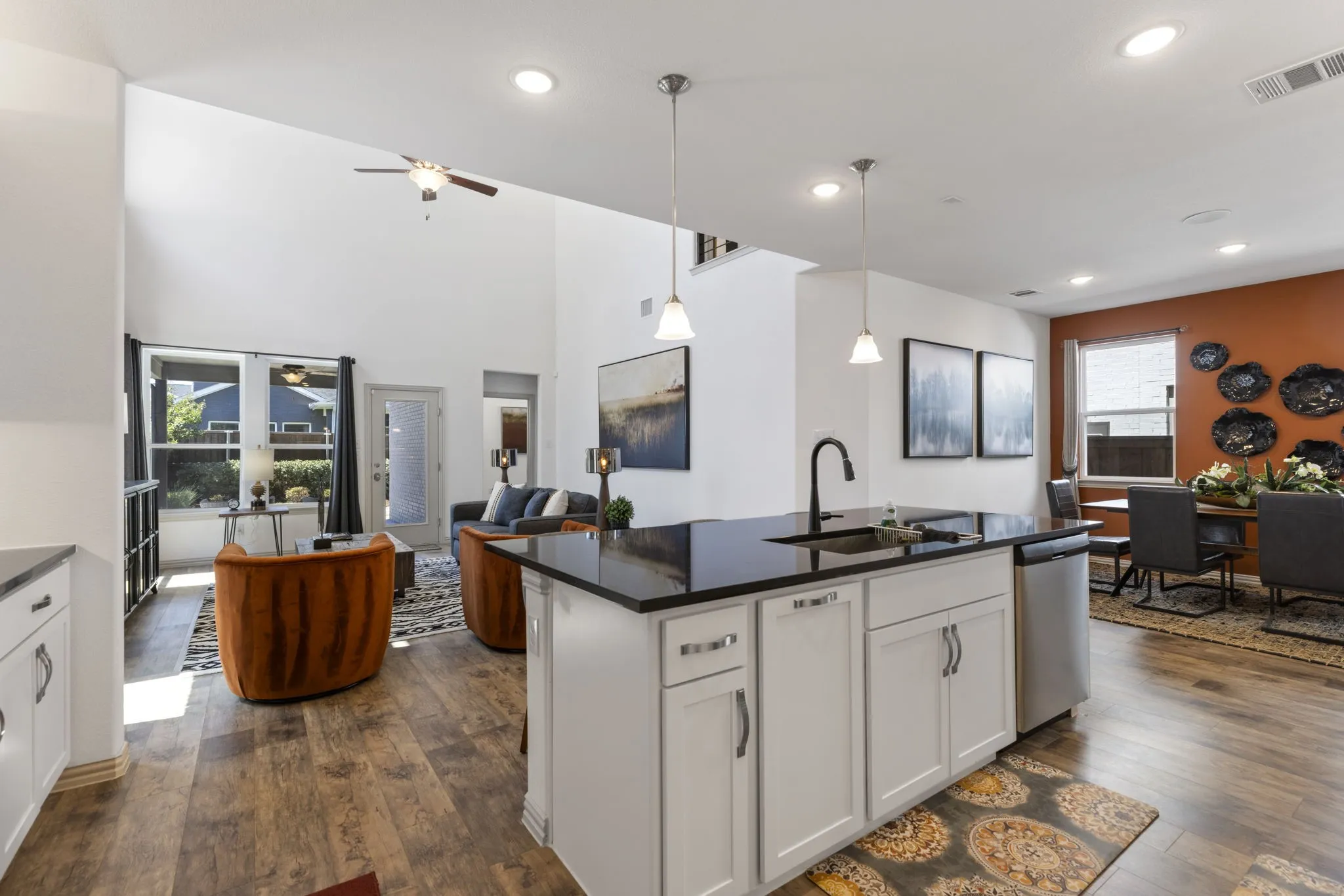 Modern kitchen island with dark countertop, white cabinetry, and a black gooseneck faucet