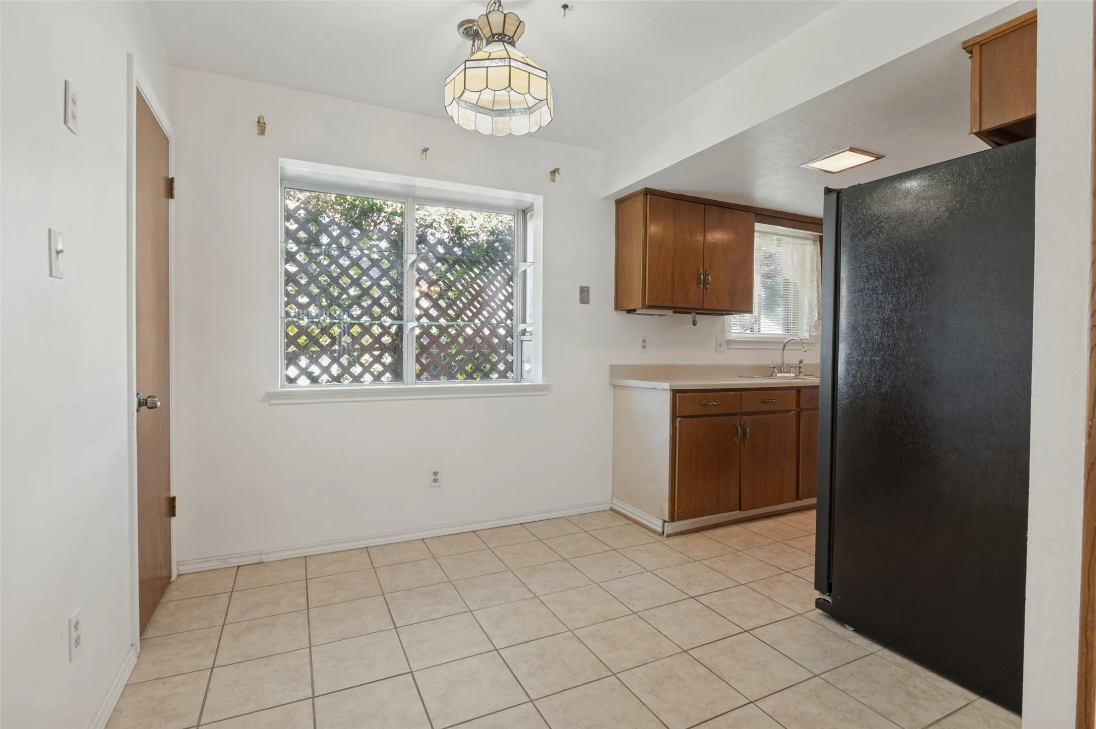 Kitchen dining area featuring tile flooring, a window with lattice work, and an overhead light fixture