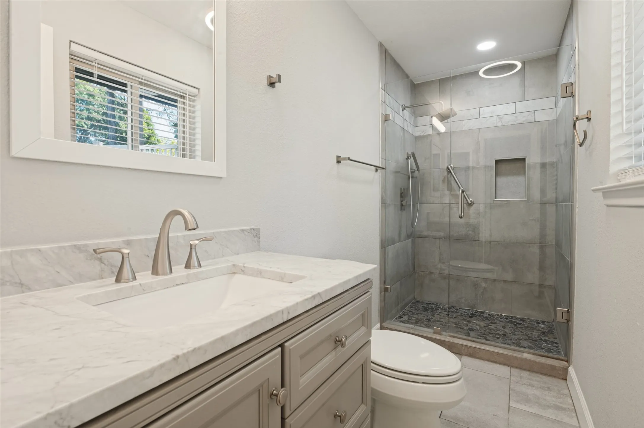 Vanity with a marble-finish countertop, undermount sink, and brushed nickel faucet